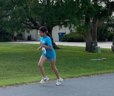 A girl in a blue shirt is running down the street