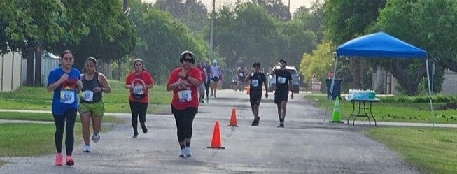 A group of people are running down a street in the rain.