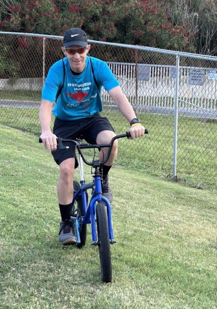 A man is riding a blue bike on a grassy hill.