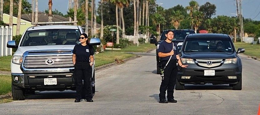 A couple of police officers standing in front of a row of cars