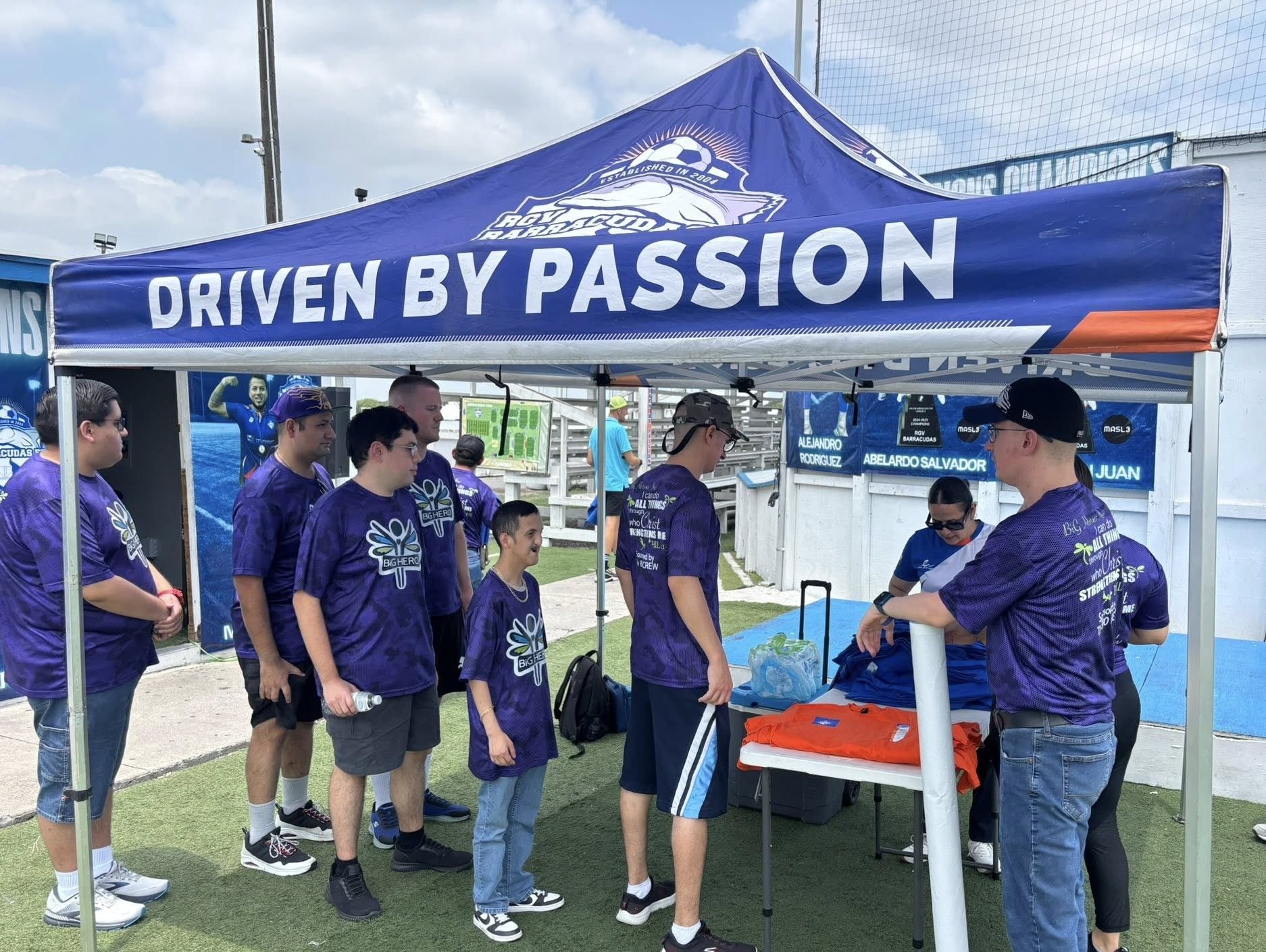 A group of people are standing under a tent that says driven by passion.