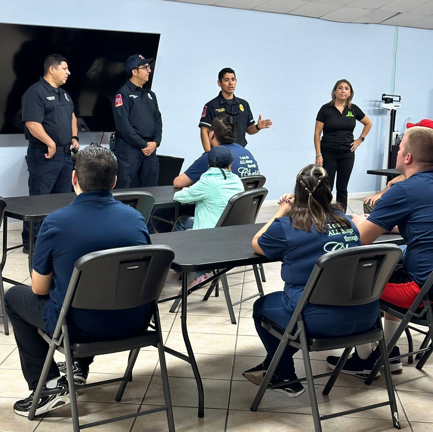 A group of people are sitting at tables and chairs in a room.