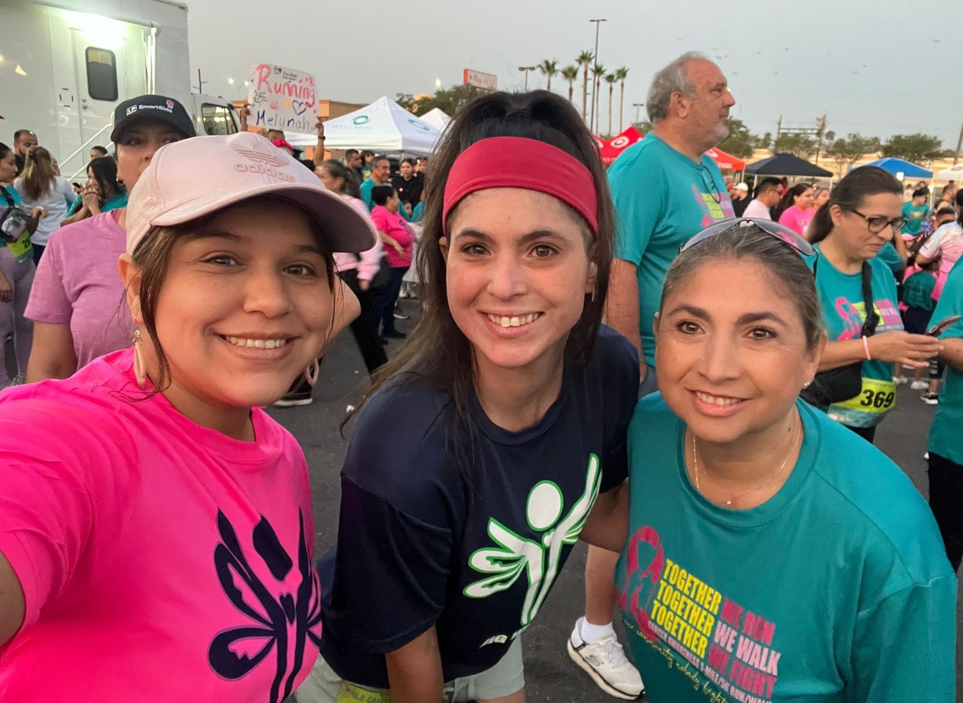 Three women are posing for a picture at a breast cancer walk.