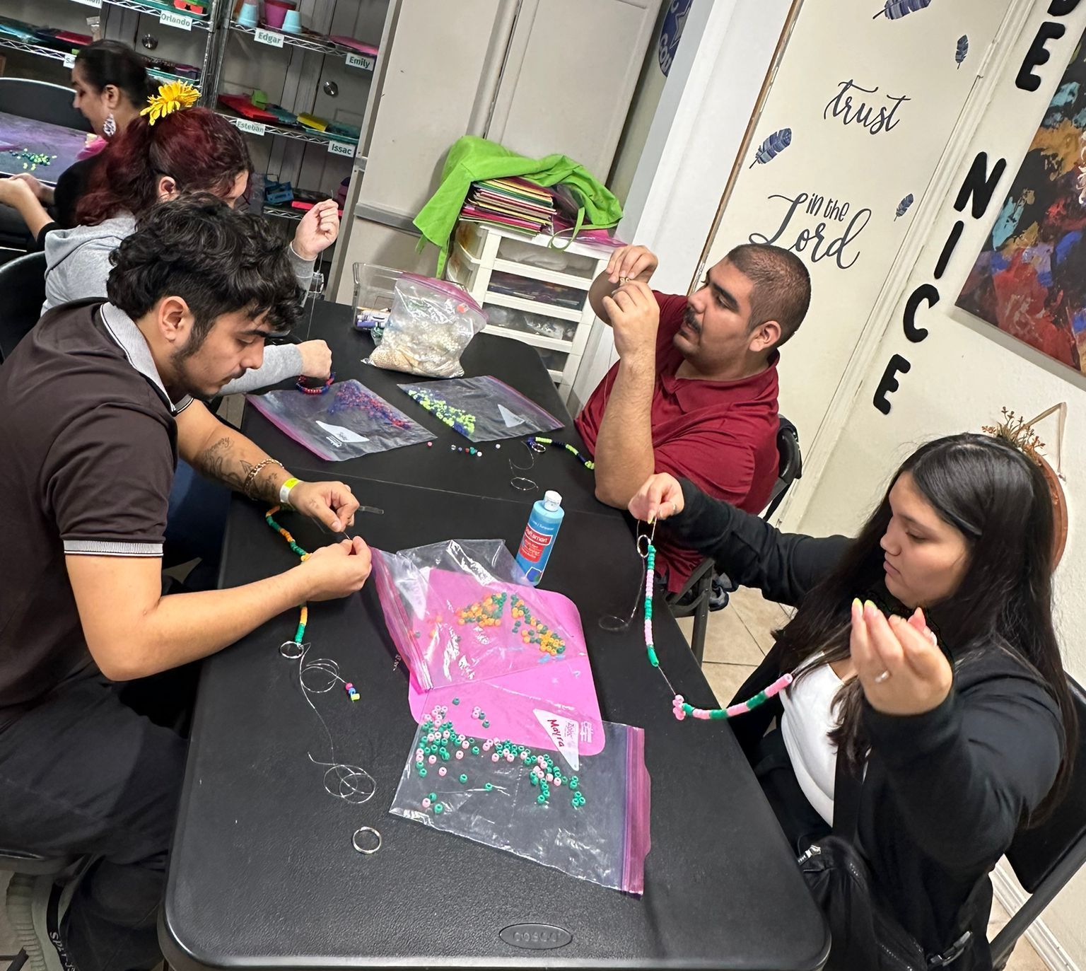 A group of people are sitting around a table making bracelets