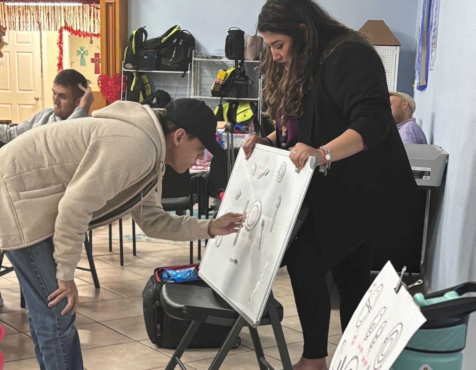 A man and a woman are looking at a drawing on a whiteboard.