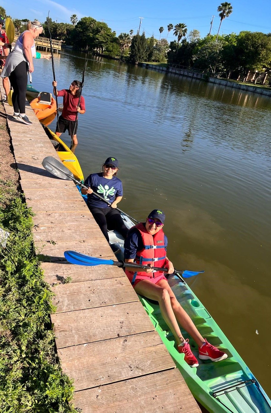 A group of people are sitting in kayaks on a dock.