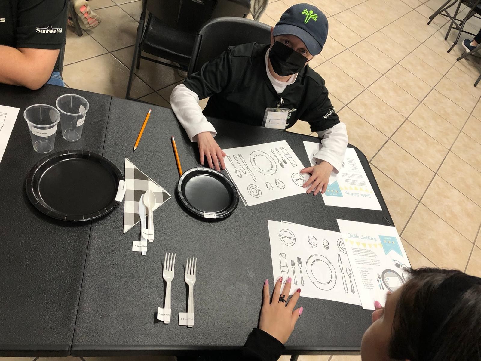 A group of children are sitting at a table with plates and silverware.