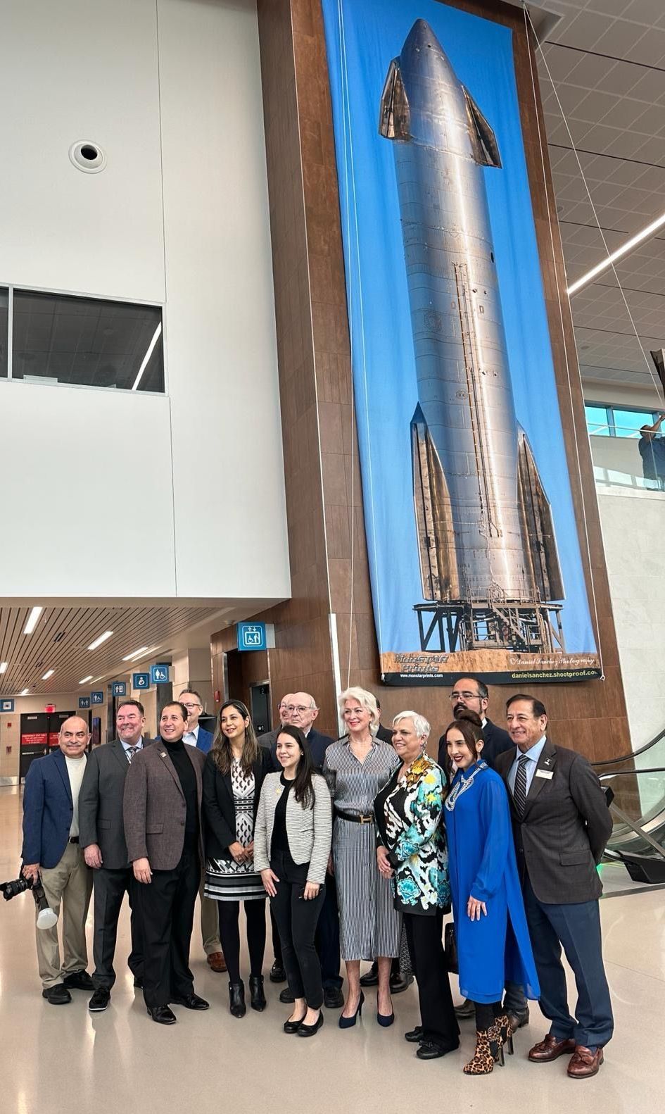 A group of people are posing for a picture in front of a large rocket.