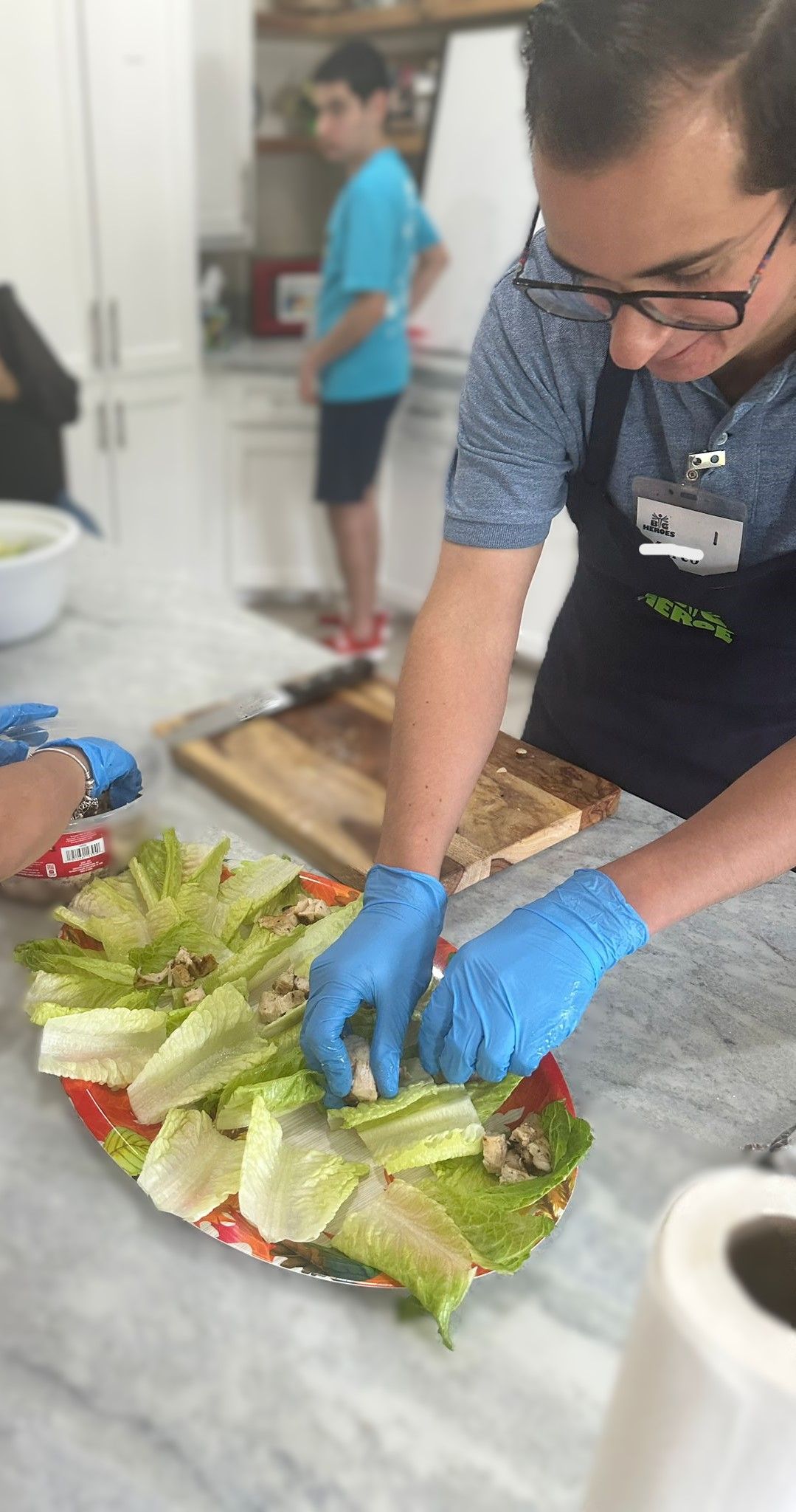A man is cutting lettuce on a plate in a kitchen.