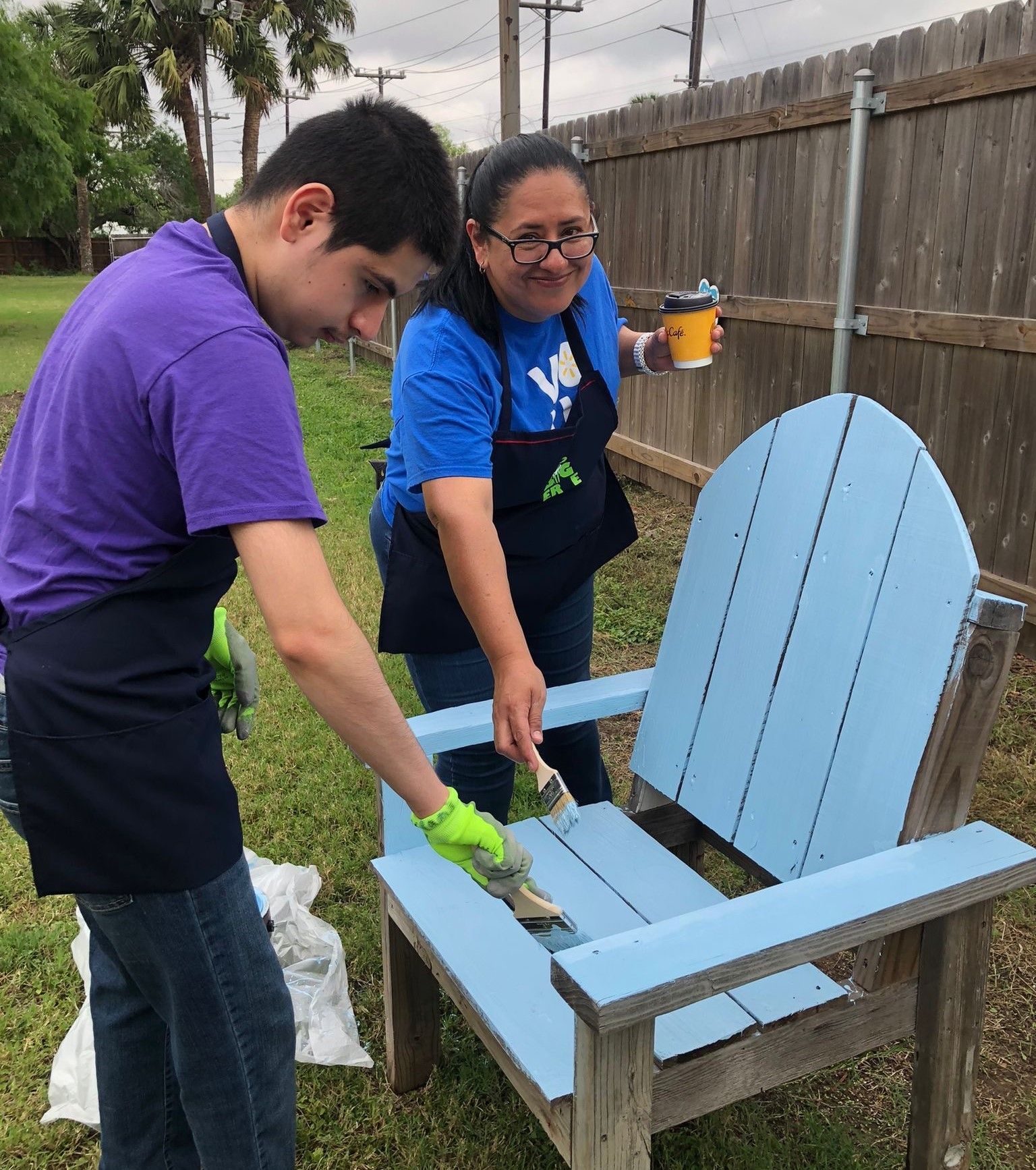 A man and a woman are painting a blue chair