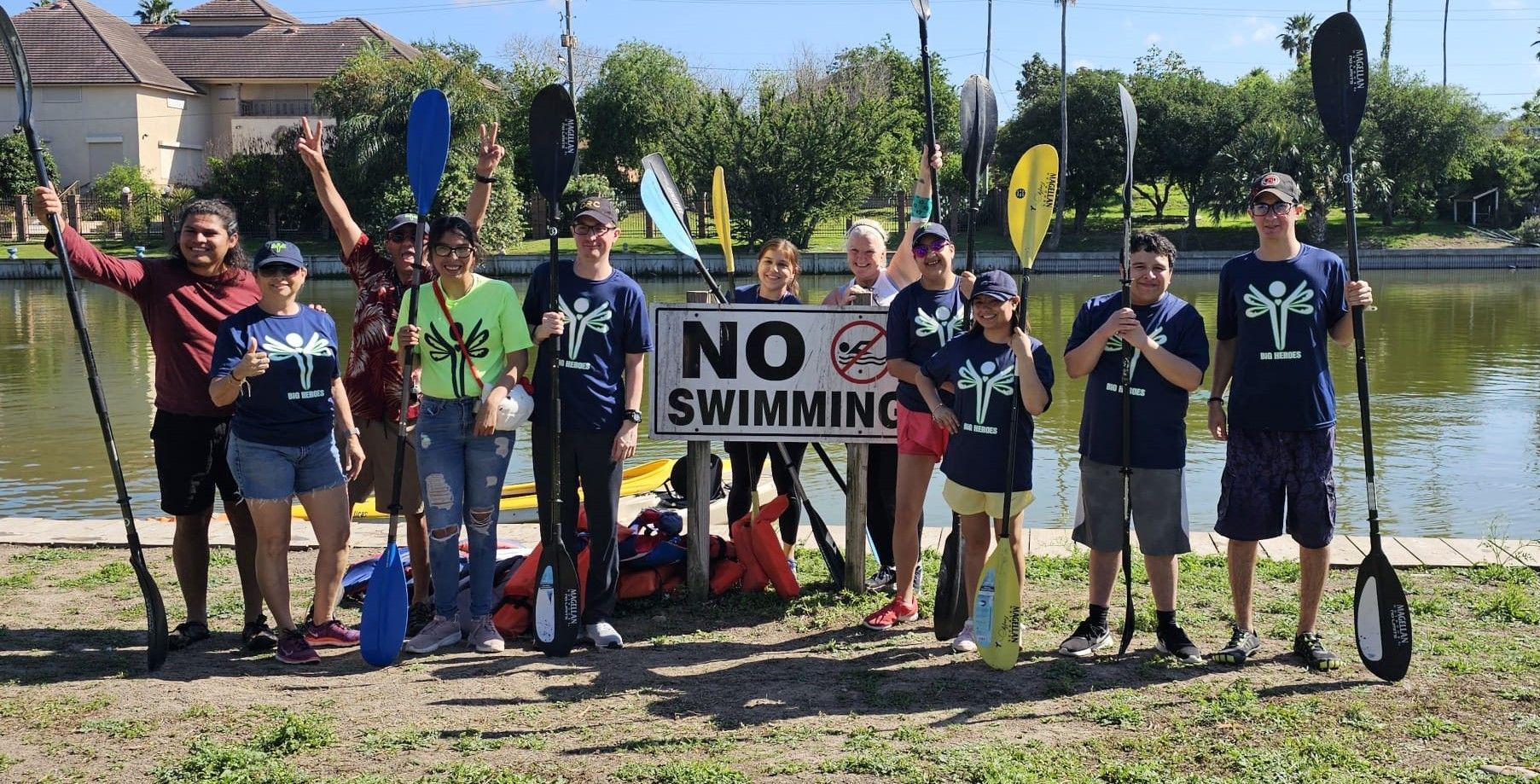 A group of people holding kayaks and a sign that says no swimming.