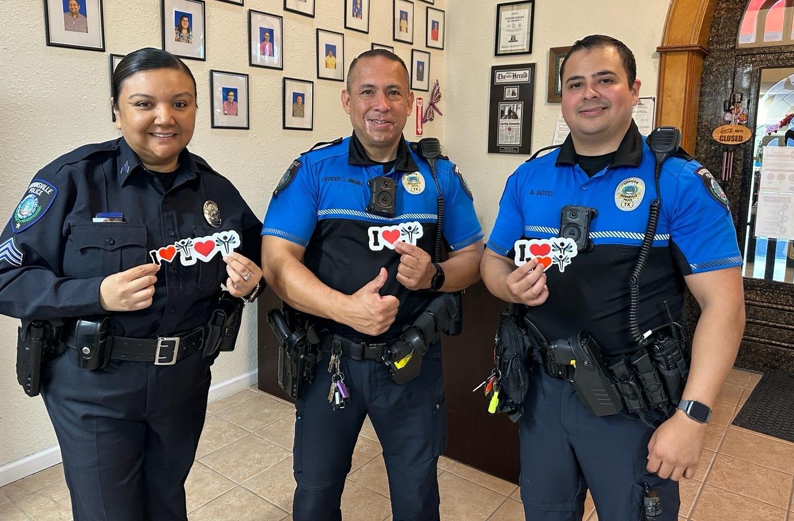 Three police officers are standing next to each other and giving a thumbs up.