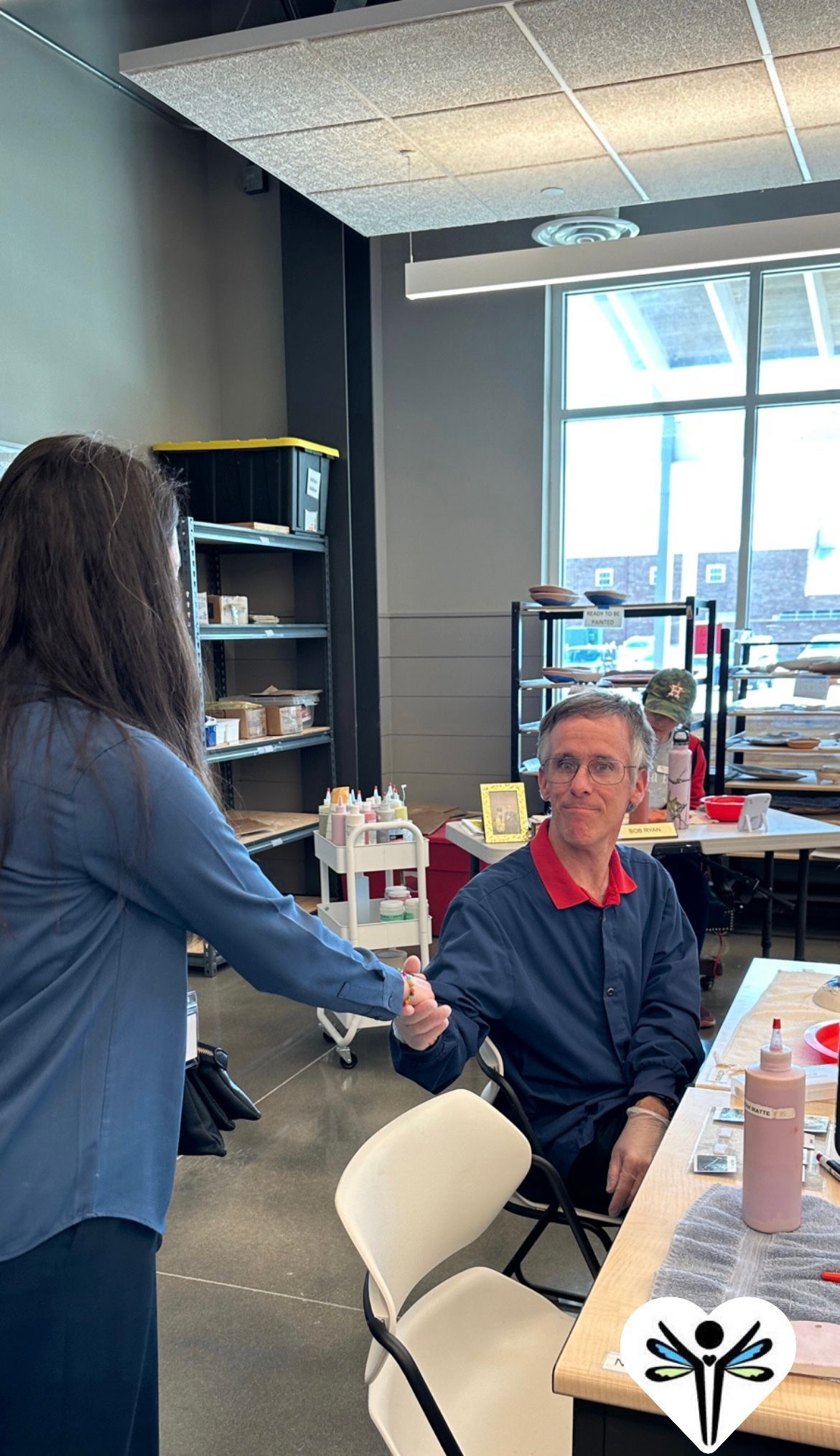 A woman is shaking hands with a man sitting at a table.