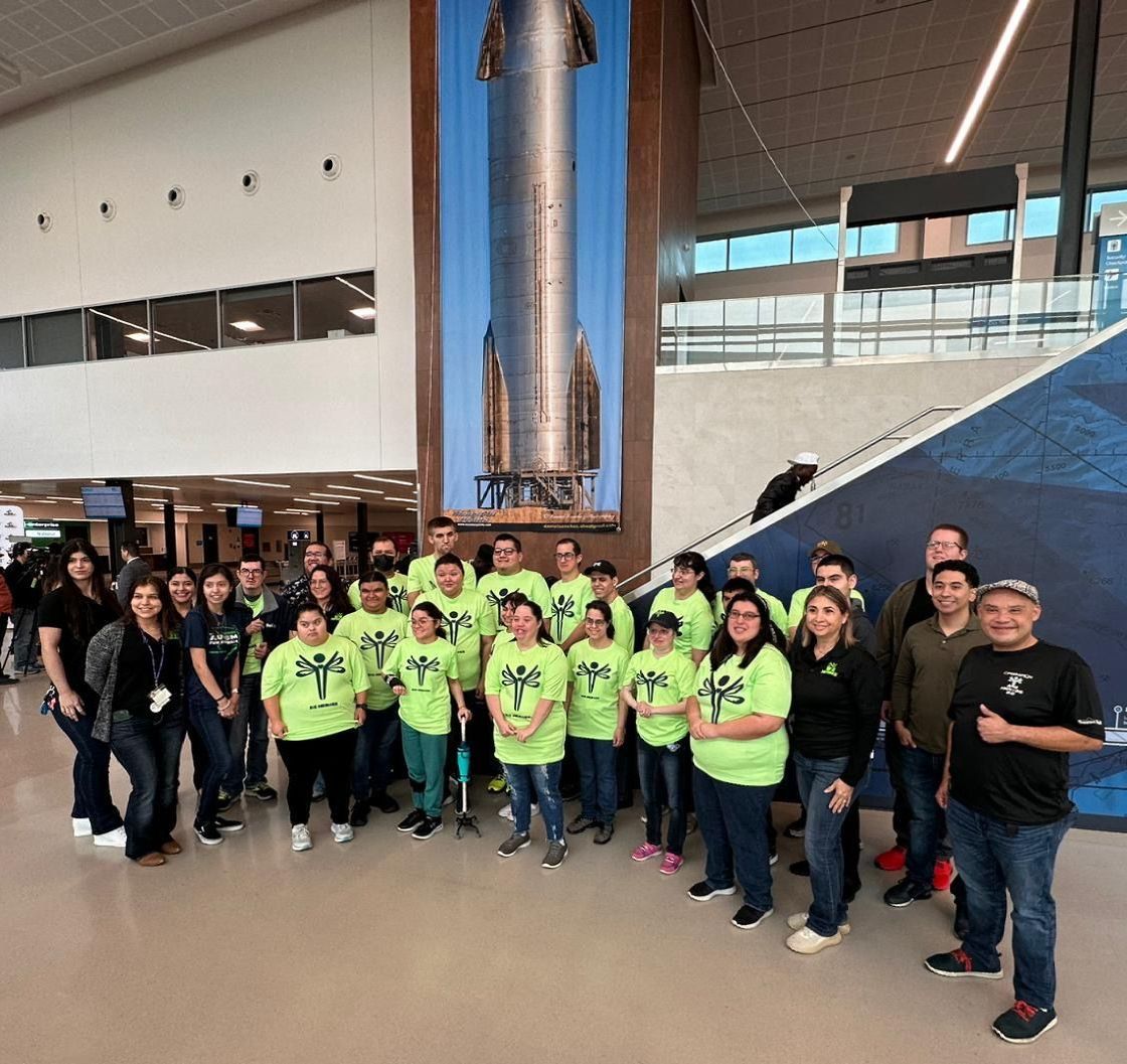 A group of people posing for a picture in front of a rocket