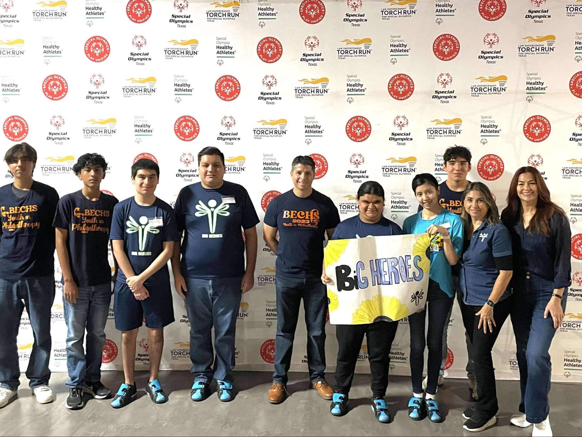 A group of people are posing for a picture in front of a wall.
