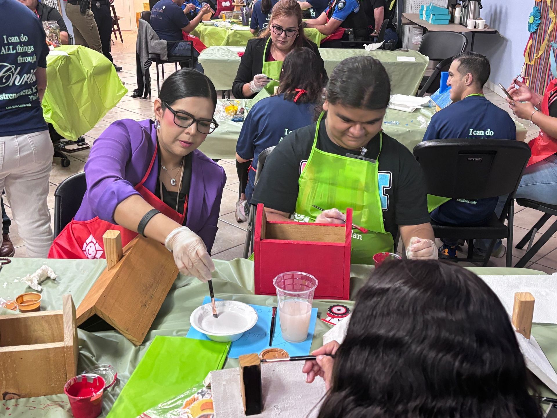 A group of people are sitting at tables making crafts.