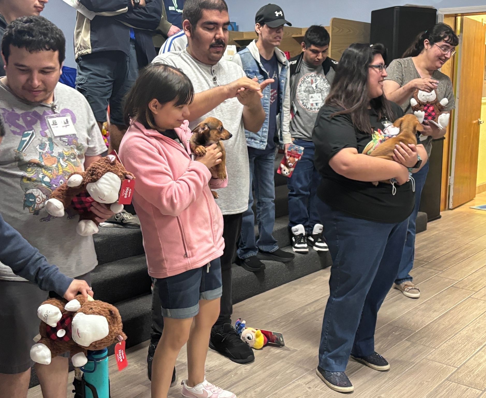 A group of people are standing in a room holding stuffed animals.