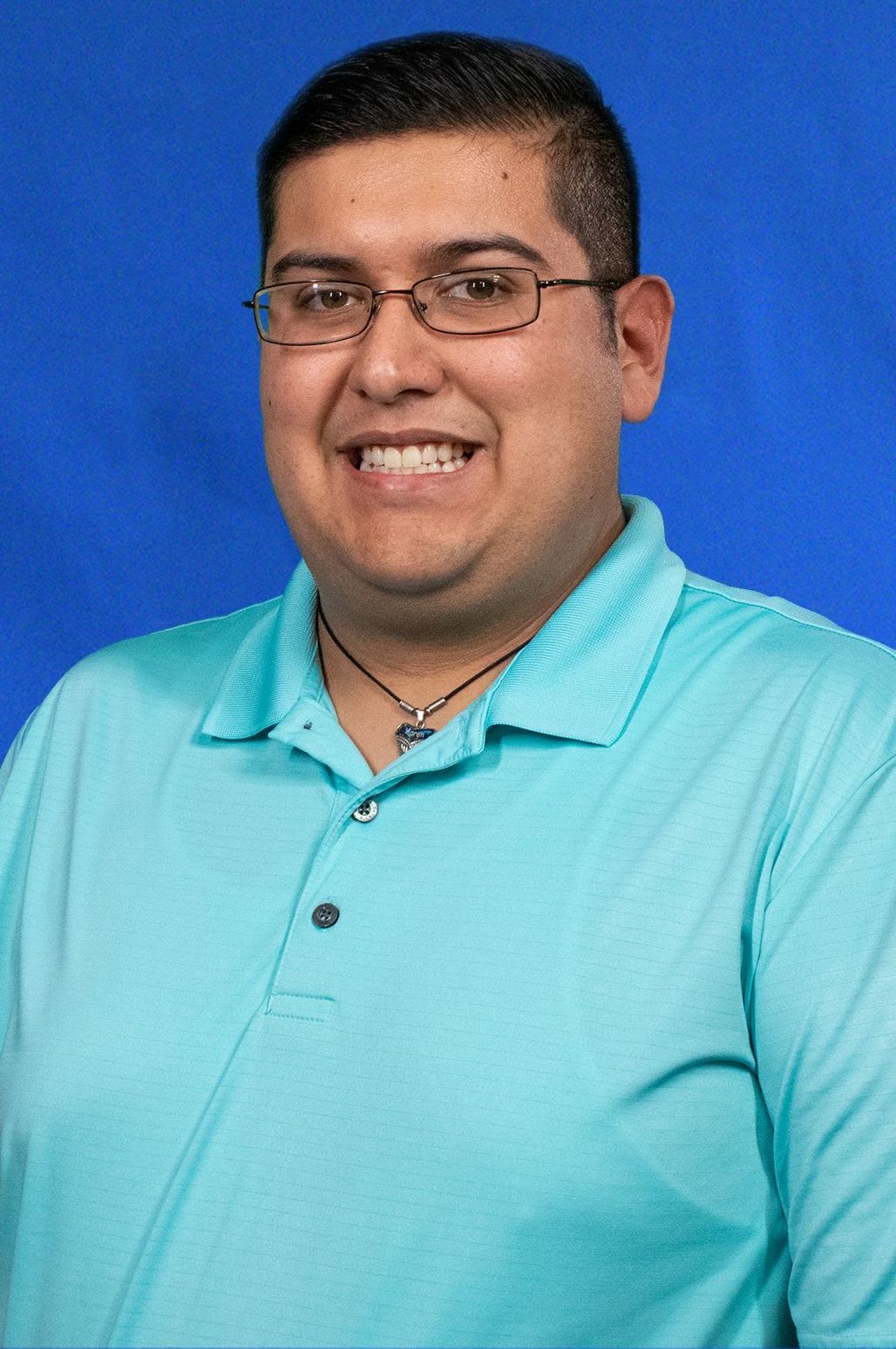 A man wearing glasses and a blue shirt is smiling for the camera.