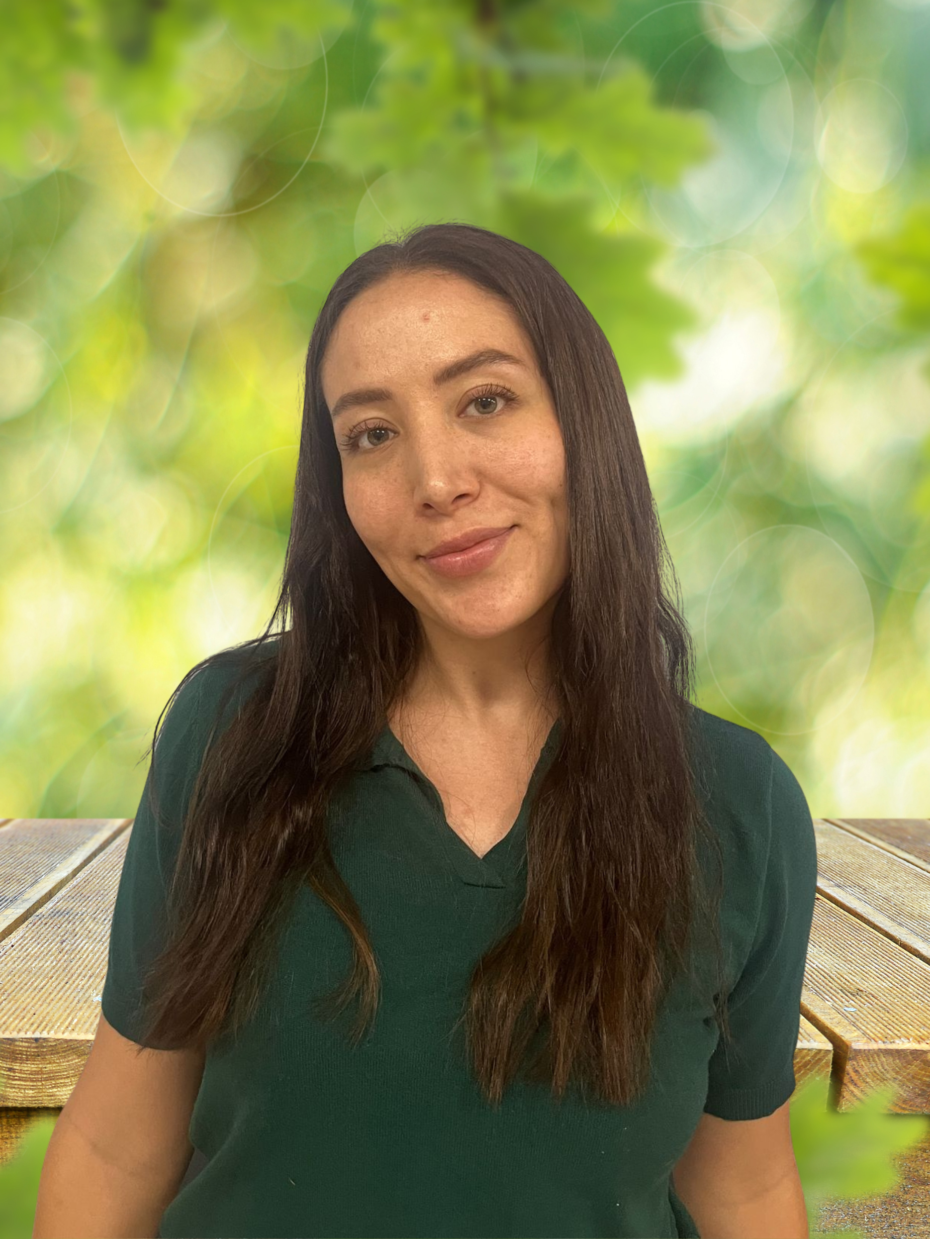 A woman in a green shirt is standing in front of a wooden table.