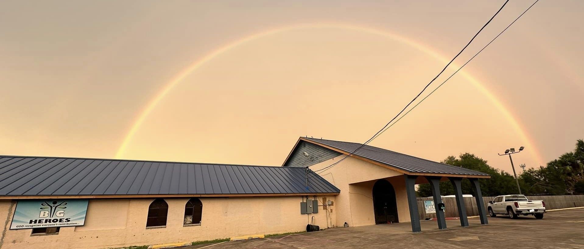 There is a rainbow in the sky over a building.