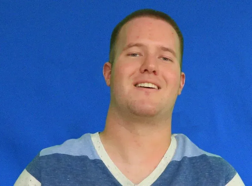 A man in a blue and white striped shirt is smiling for the camera