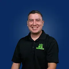 A man is wearing a black polo shirt and smiling.