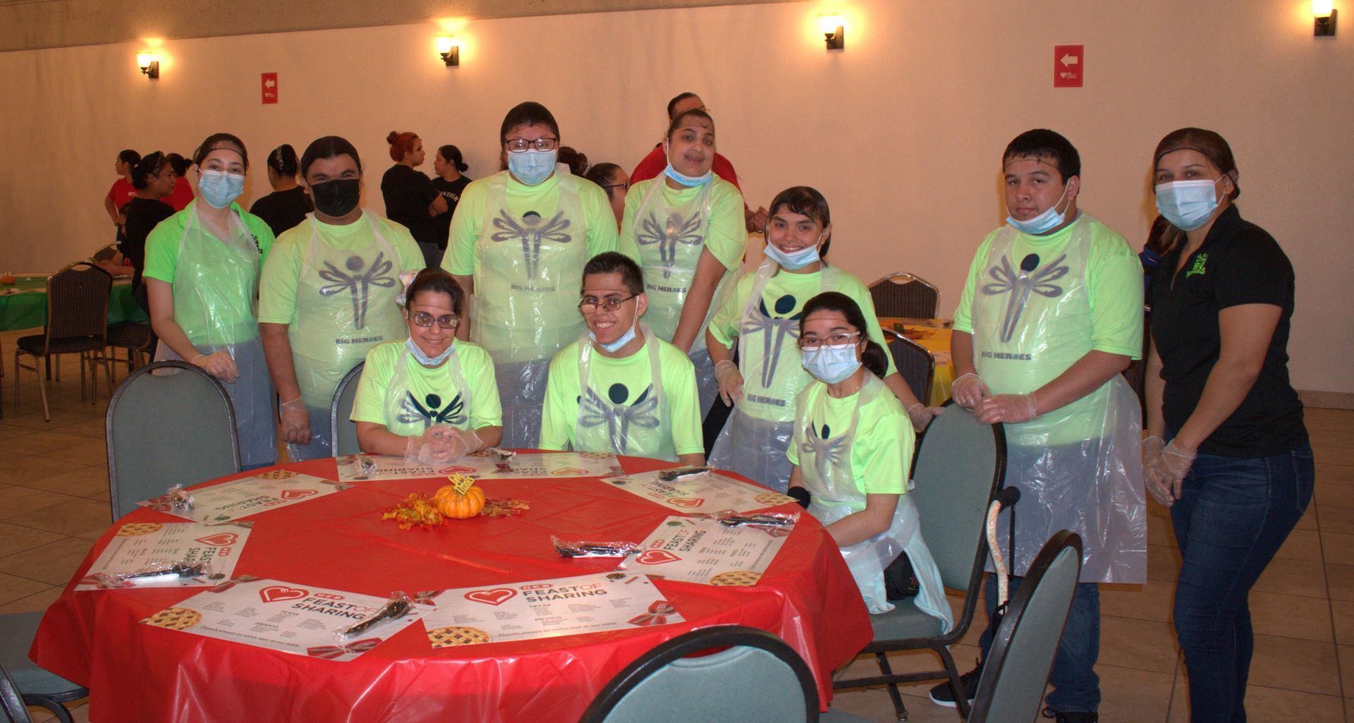 A group of people wearing masks are standing around a table