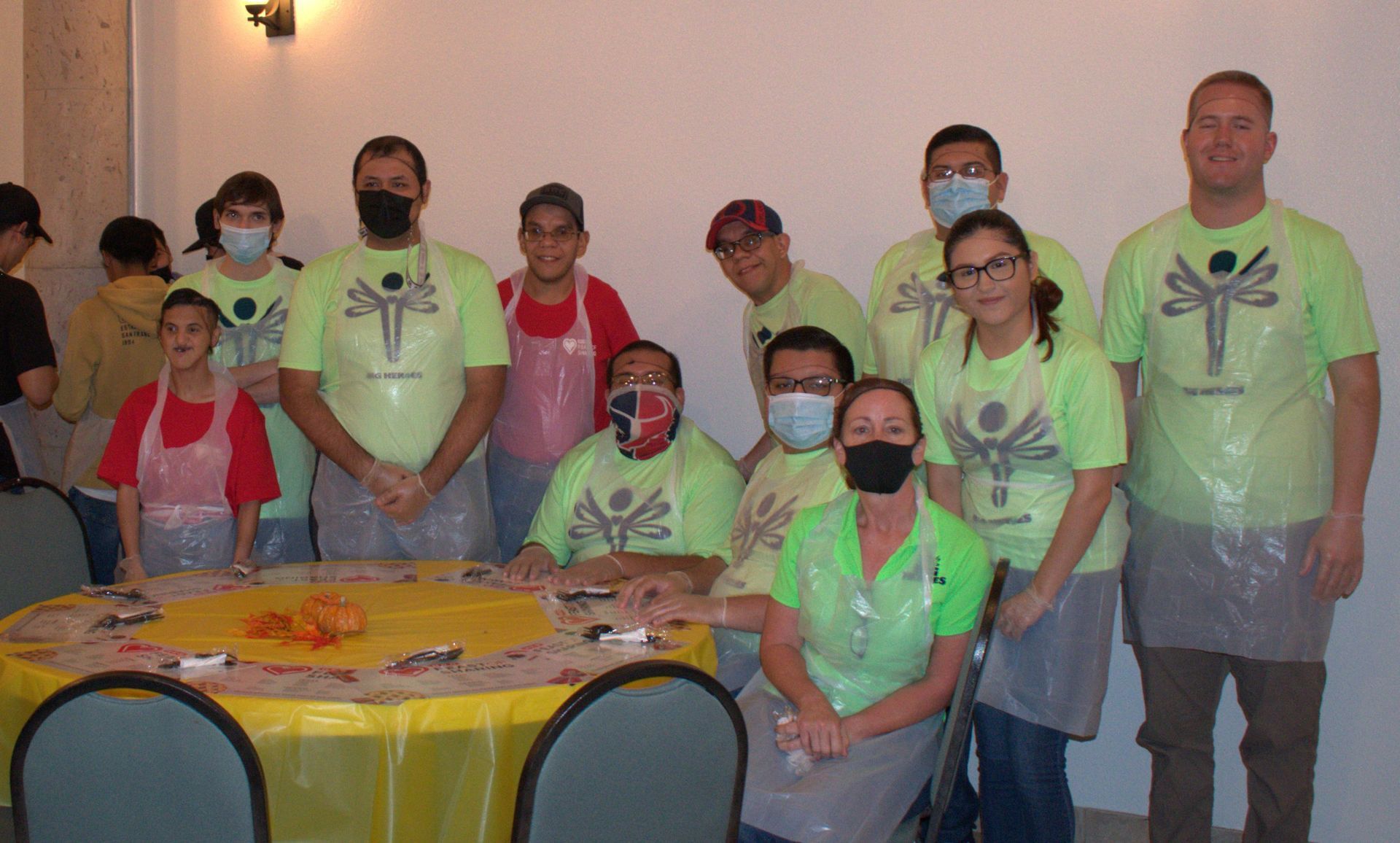 A group of people wearing masks and aprons are standing around a table.
