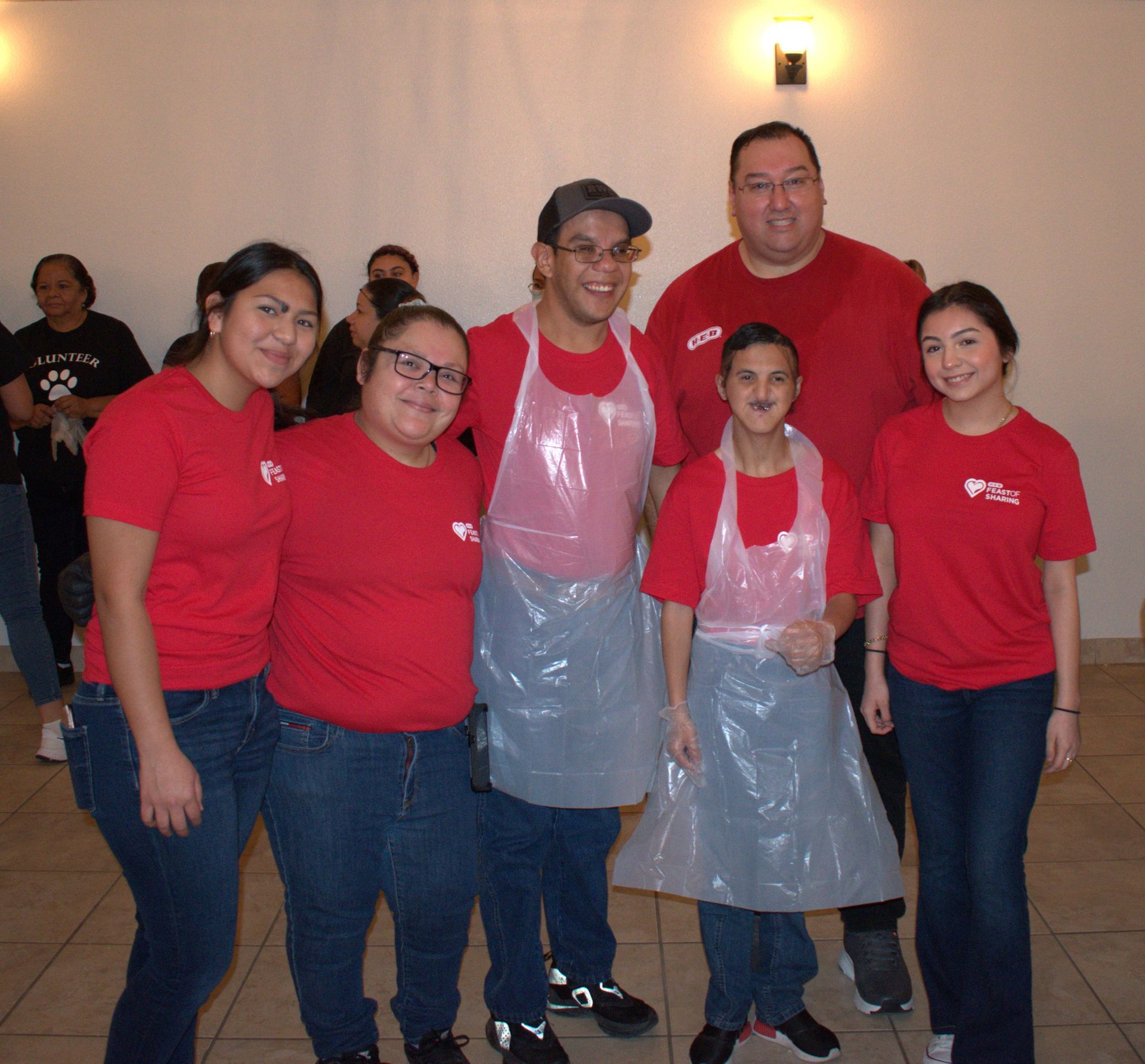 A group of people wearing red shirts and aprons are posing for a picture