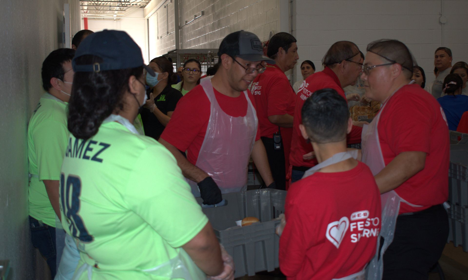 A group of people wearing red shirts and aprons are standing in a room.