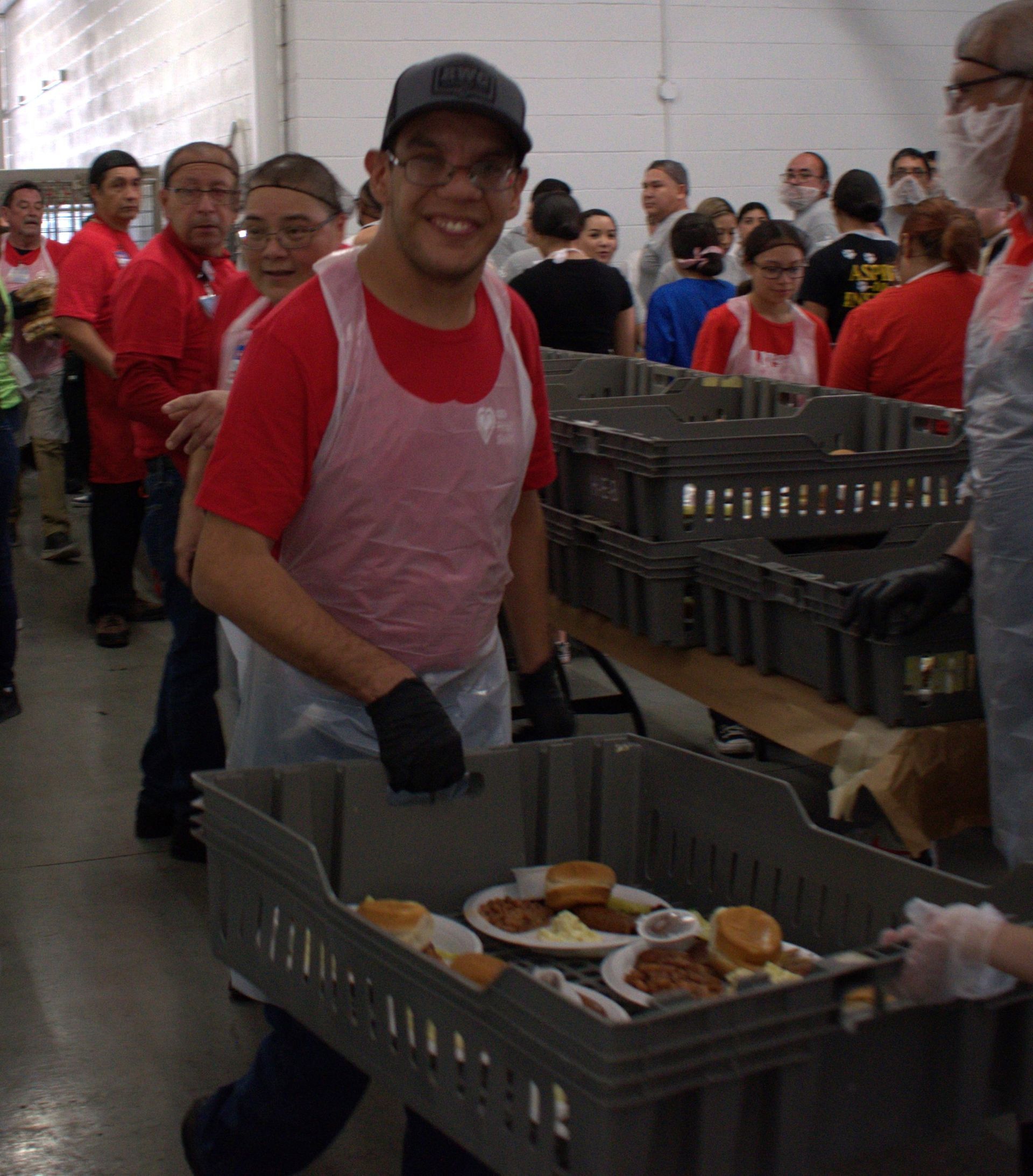 A man in a red shirt is carrying a basket full of food