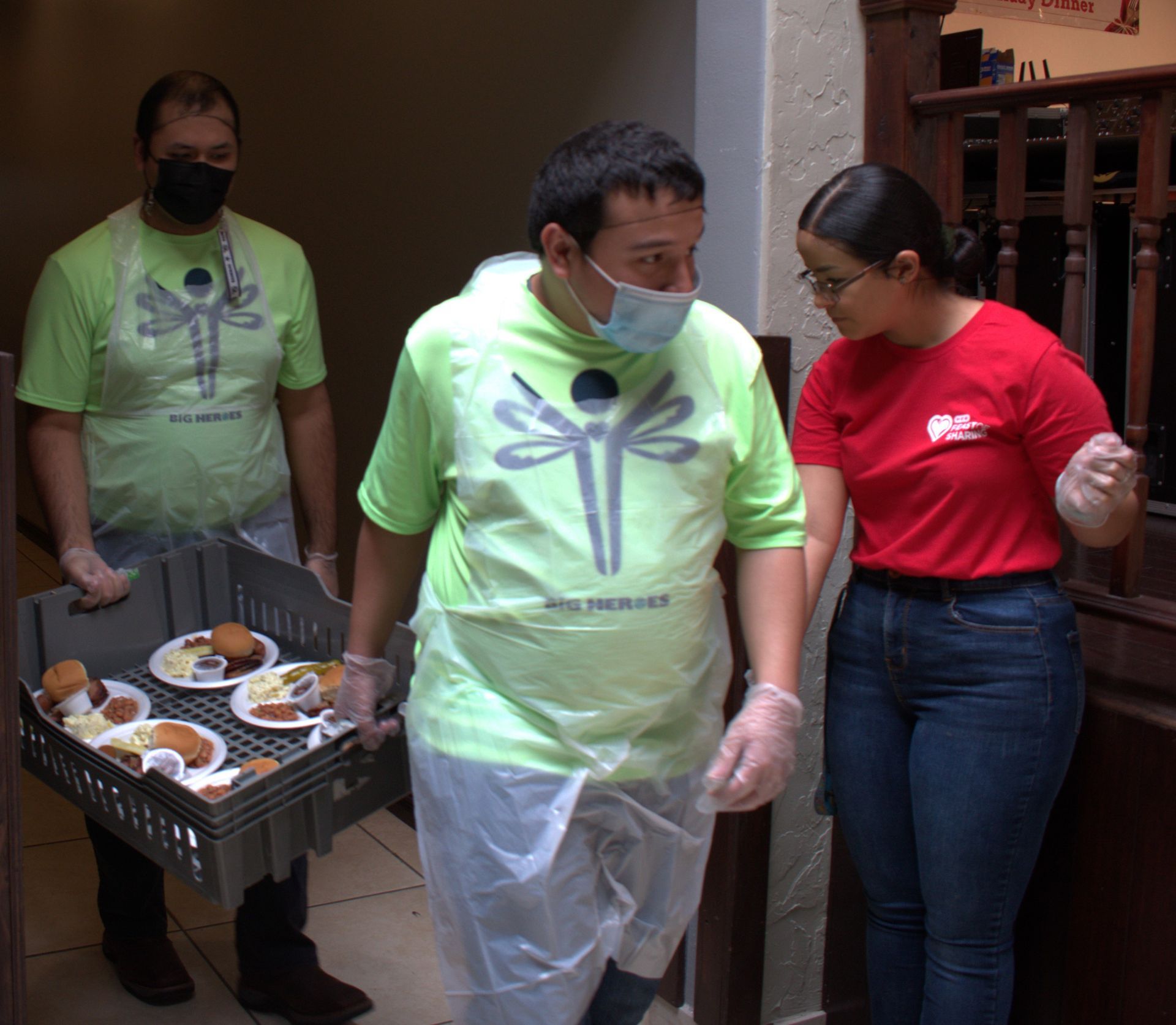 A man wearing a mask is carrying a tray of food