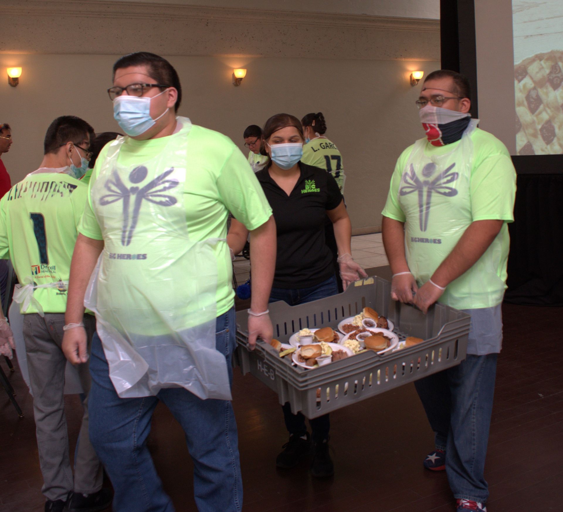 A man wearing a mask is carrying a tray of food