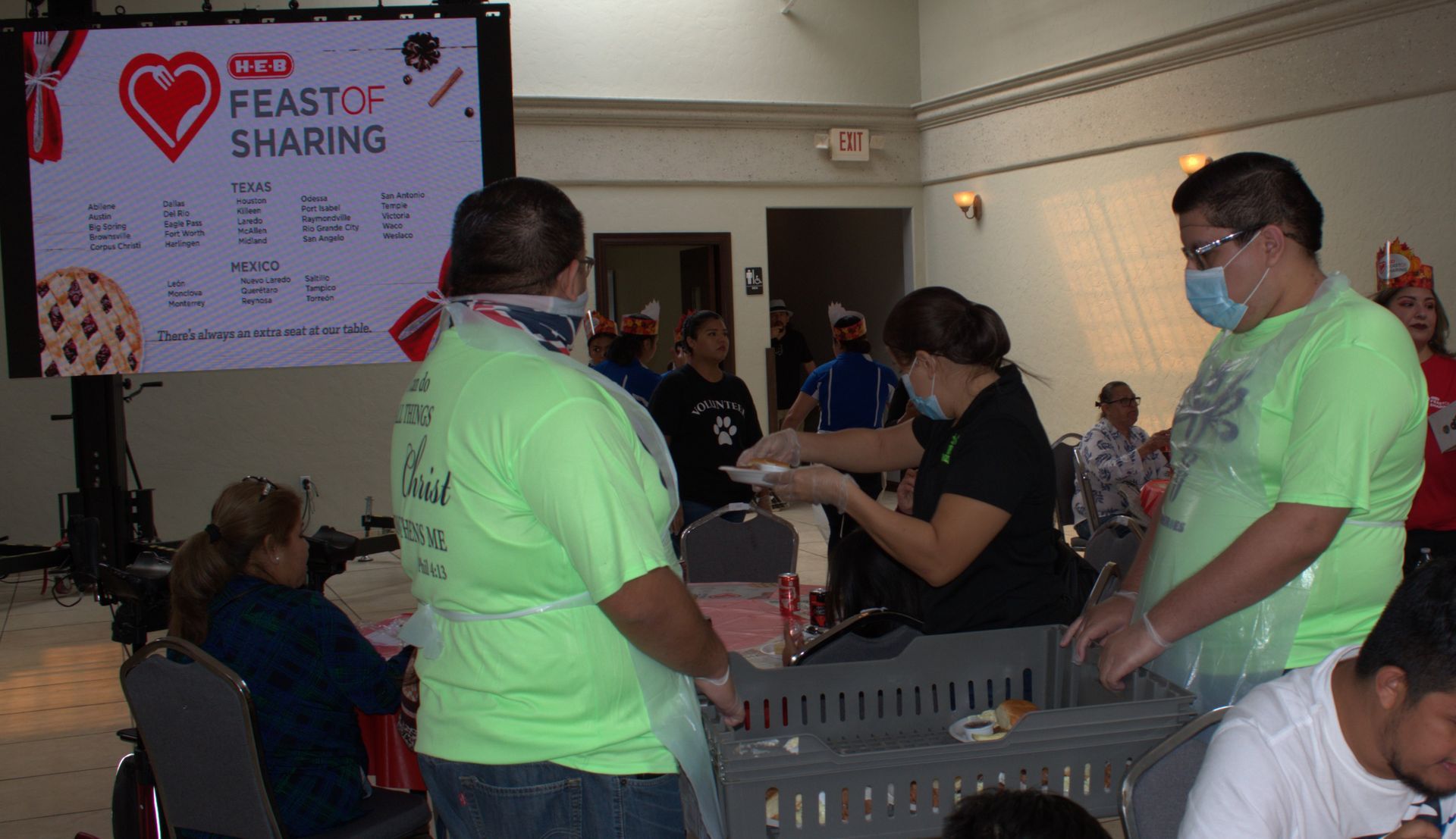 A group of people are standing in front of a sign that says feast of sharing.