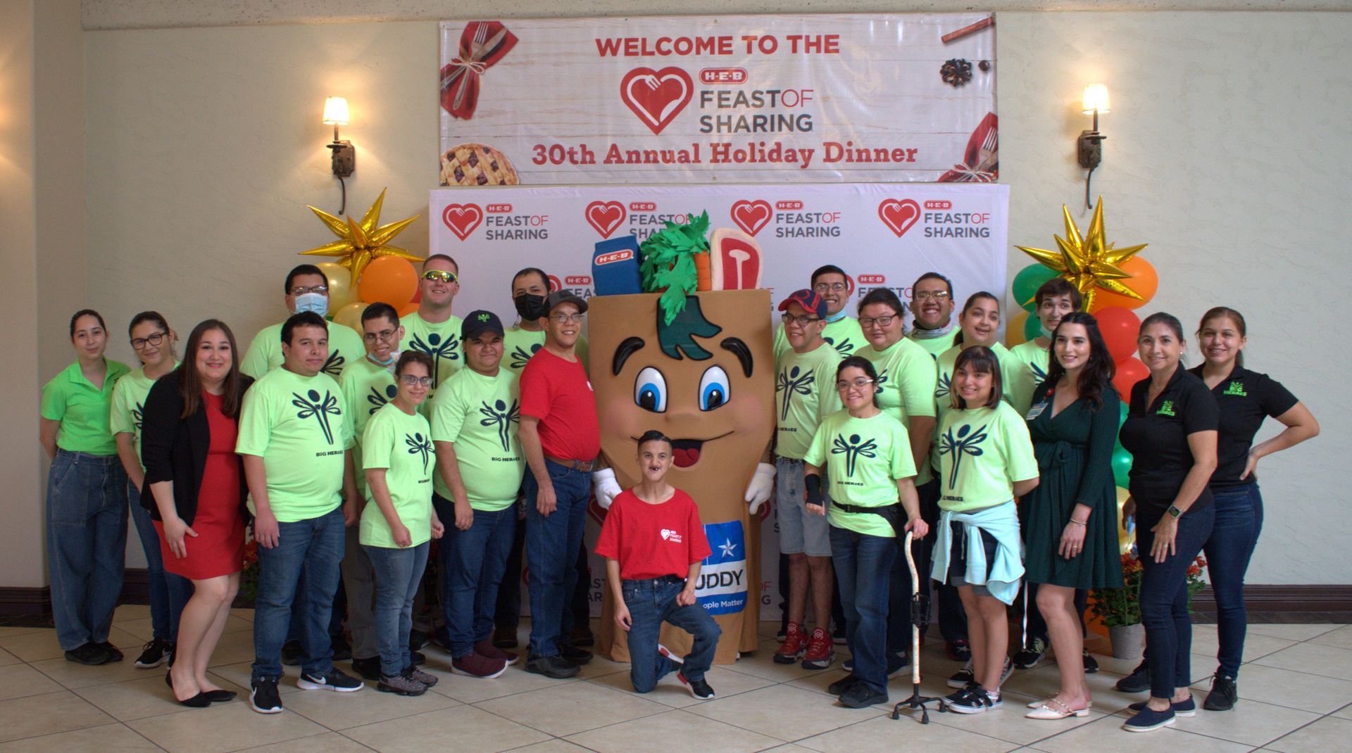 A group of people are posing for a picture in front of a sign that says welcome to the 10th annual holiday dinner.