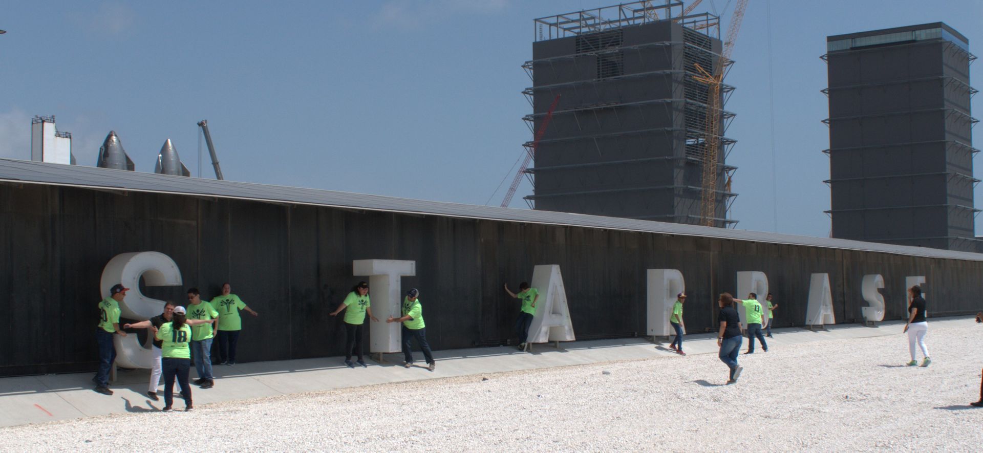 A group of people are standing in front of a wall that has the letters s and t on it