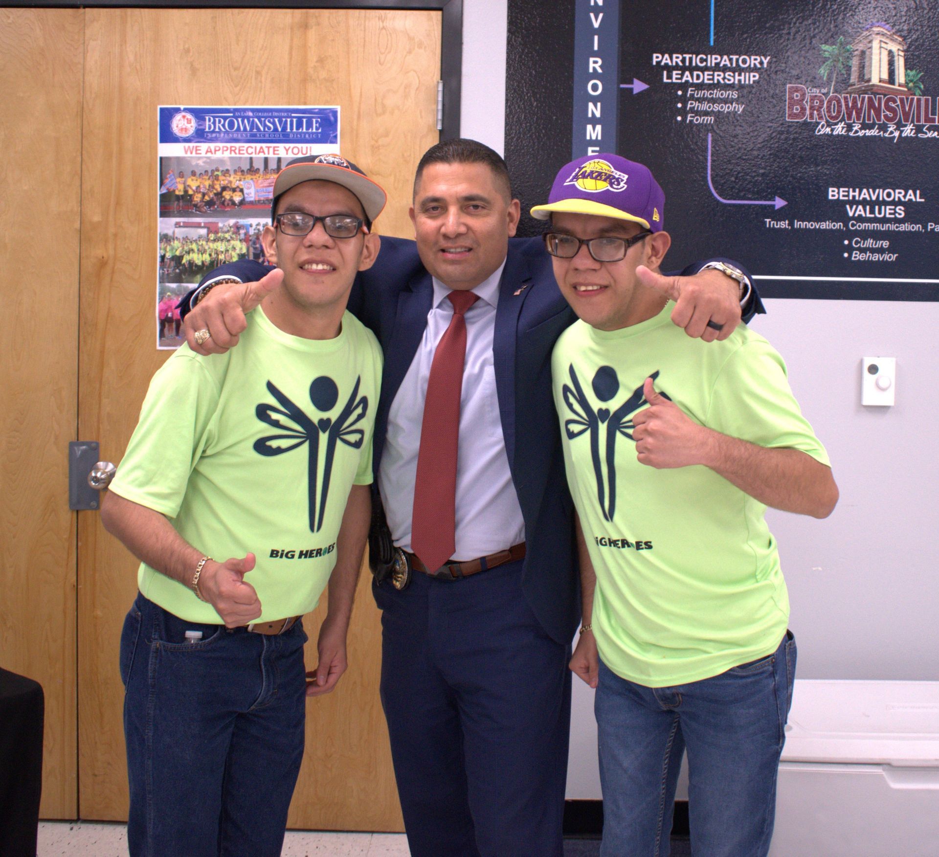 Three men posing for a picture with one wearing a purple hat