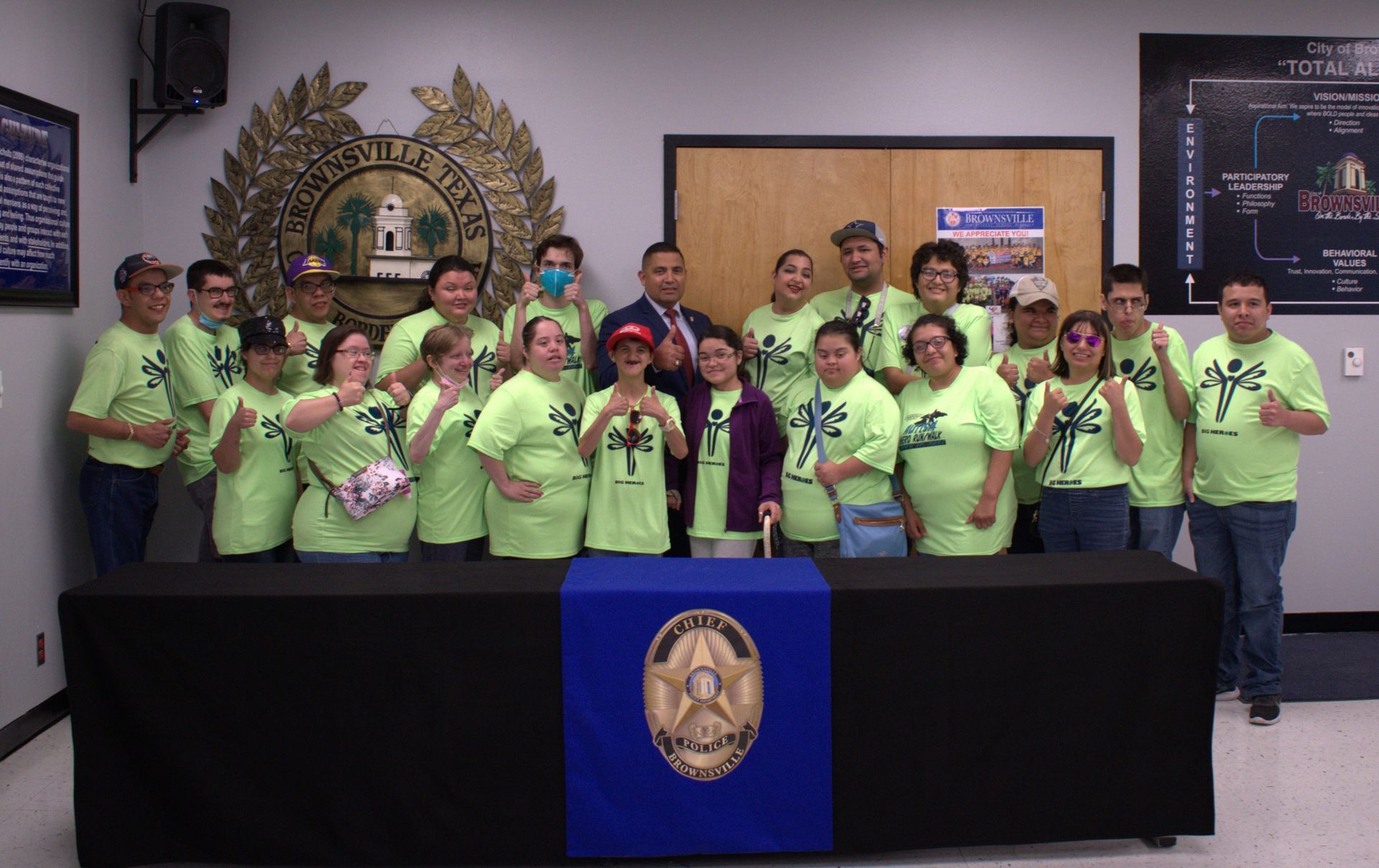 A group of people in green shirts are posing for a picture