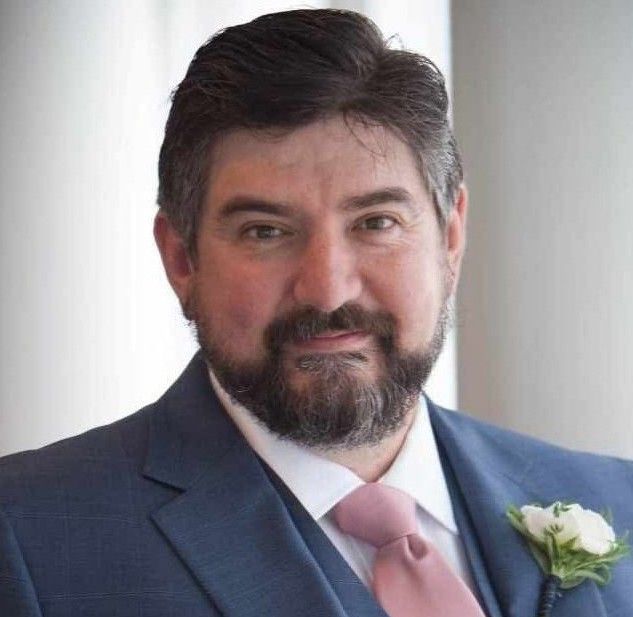 A woman wearing glasses and a jacket is smiling for the camera.