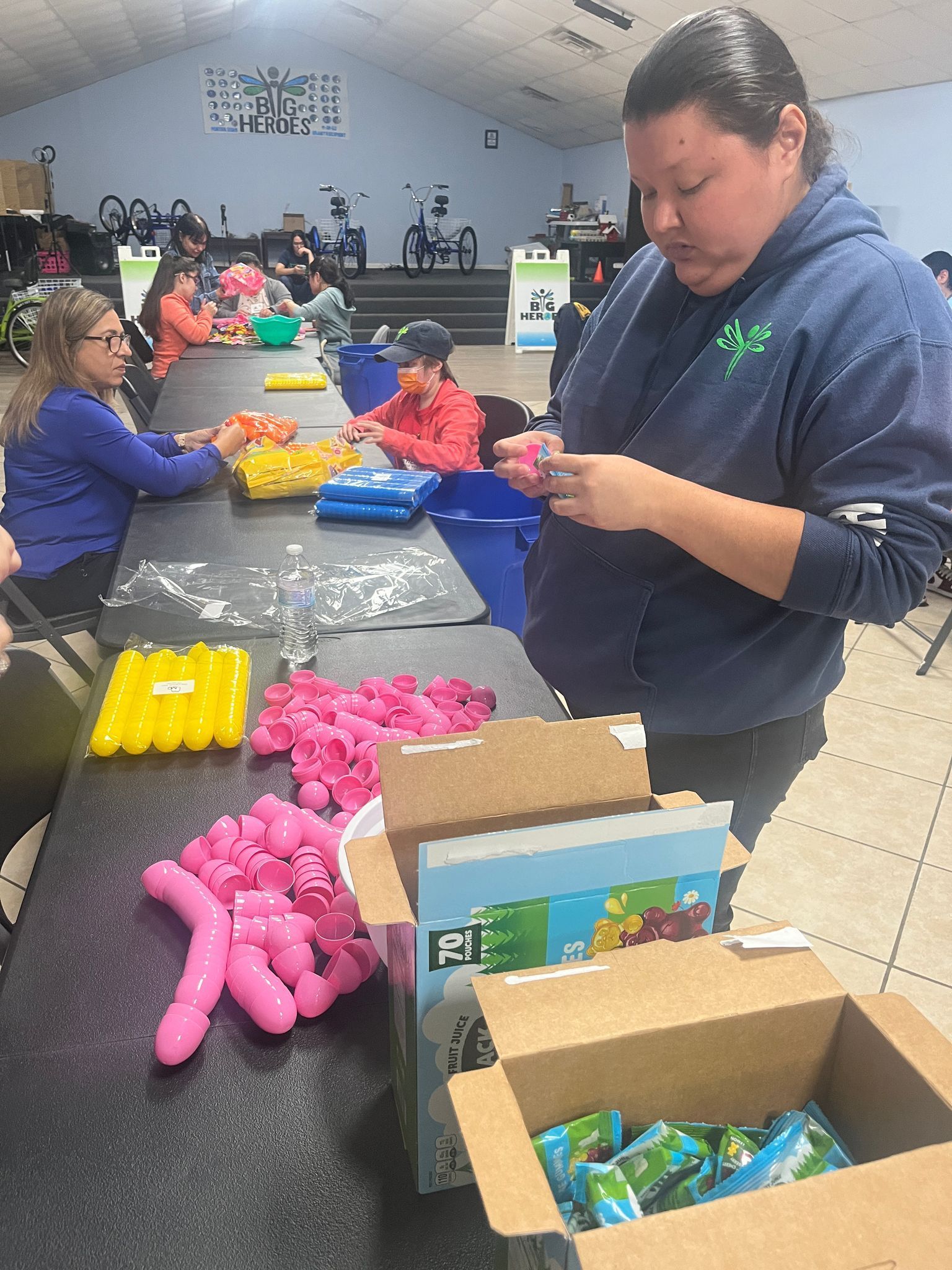 A group of people are sitting around a table making stuffed animals