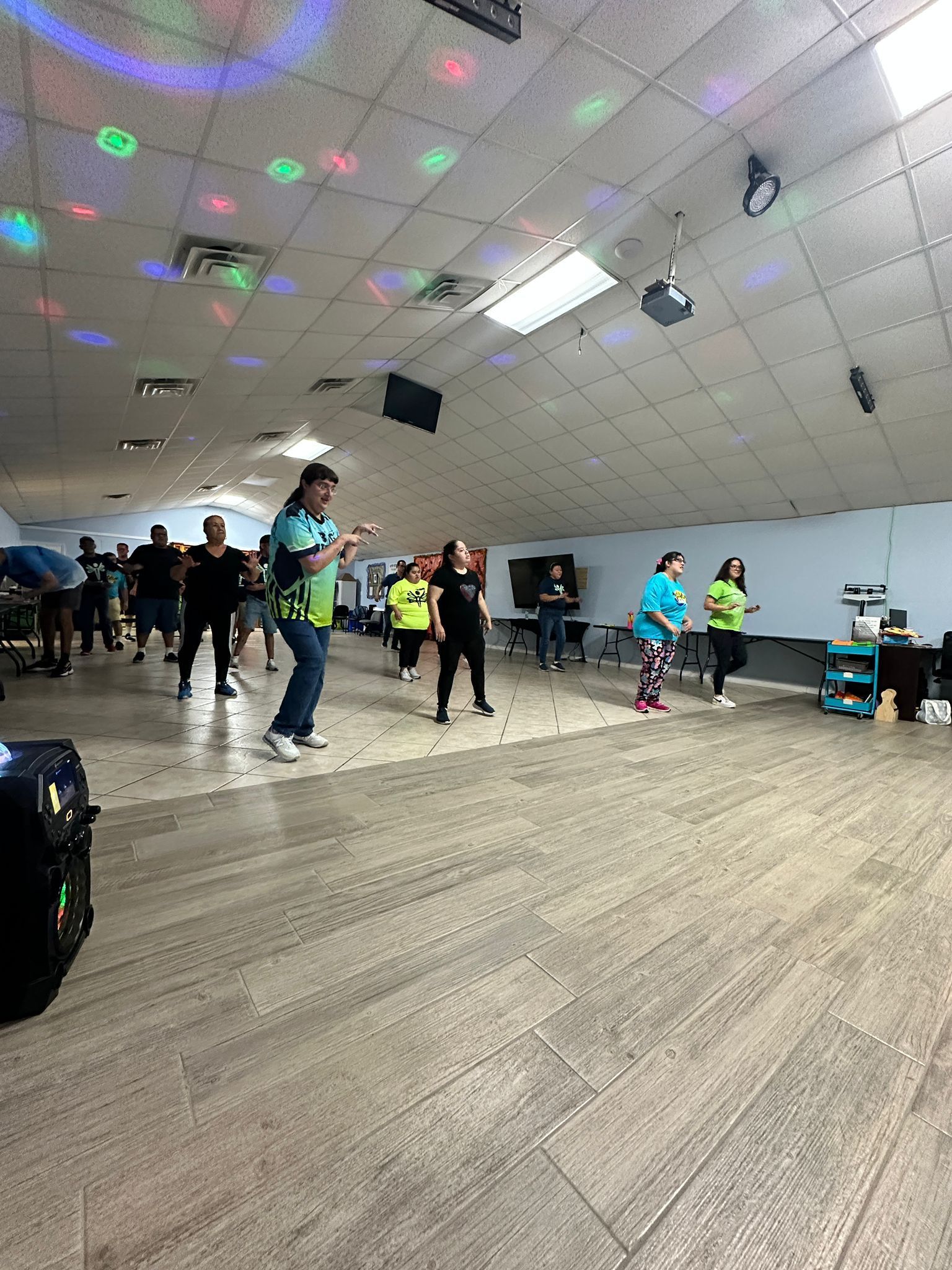 A group of people are dancing in a large room.
