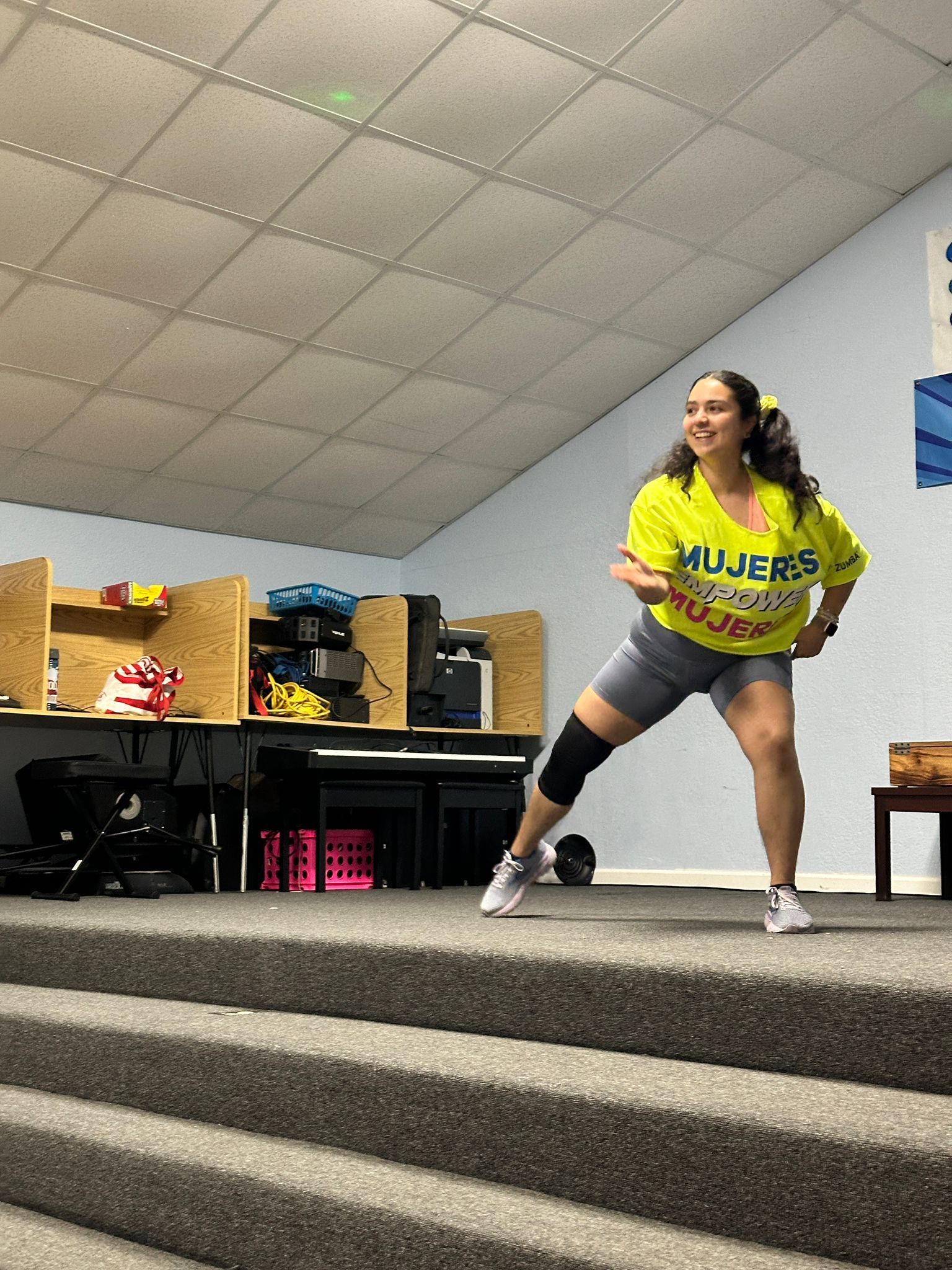 A woman in a yellow shirt is standing on a set of stairs.