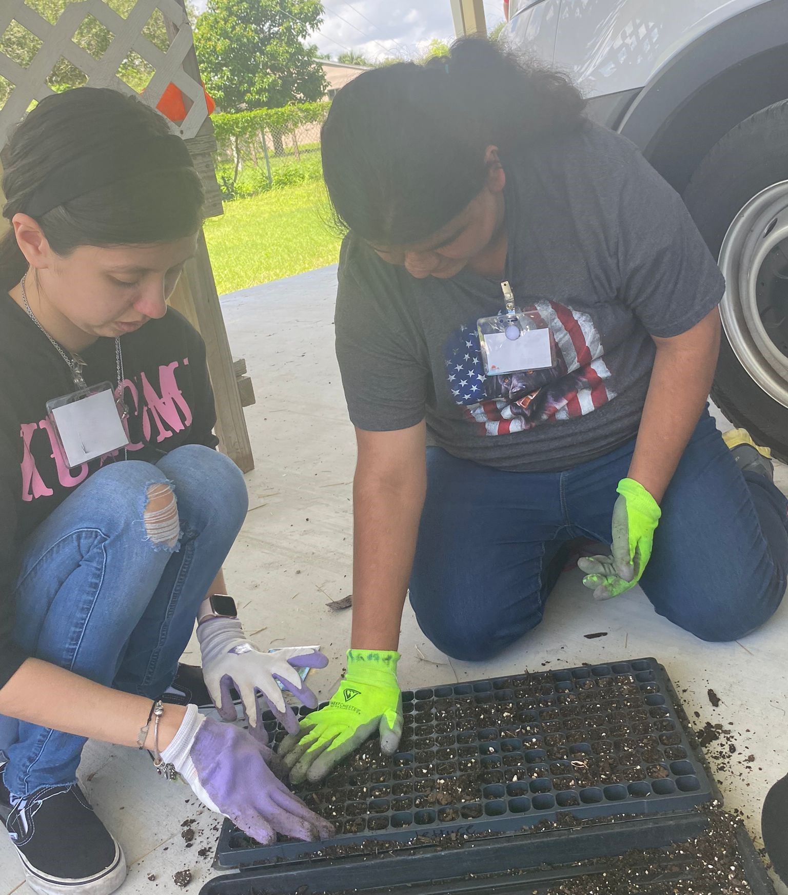A man and a woman are kneeling down to plant seeds in a tray