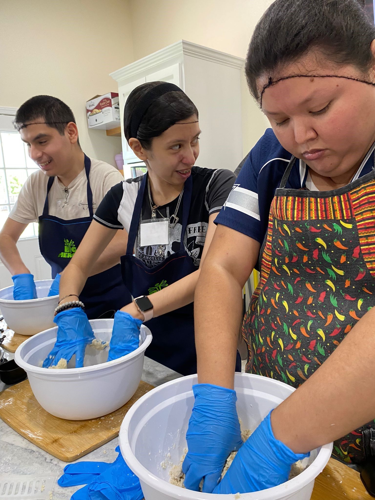A group of people are preparing food in bowls in a kitchen.