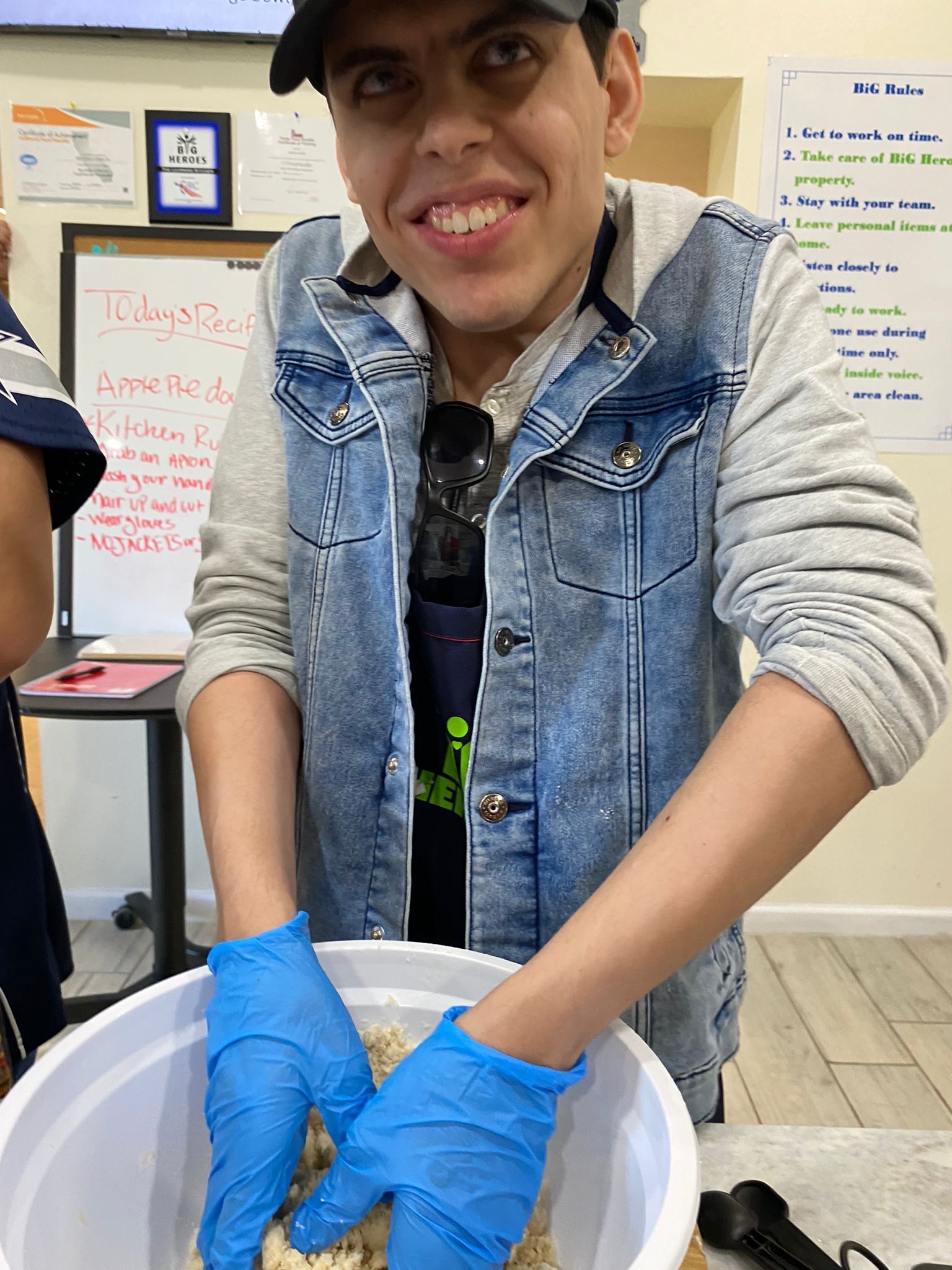 A man wearing blue gloves is holding a bowl of food.