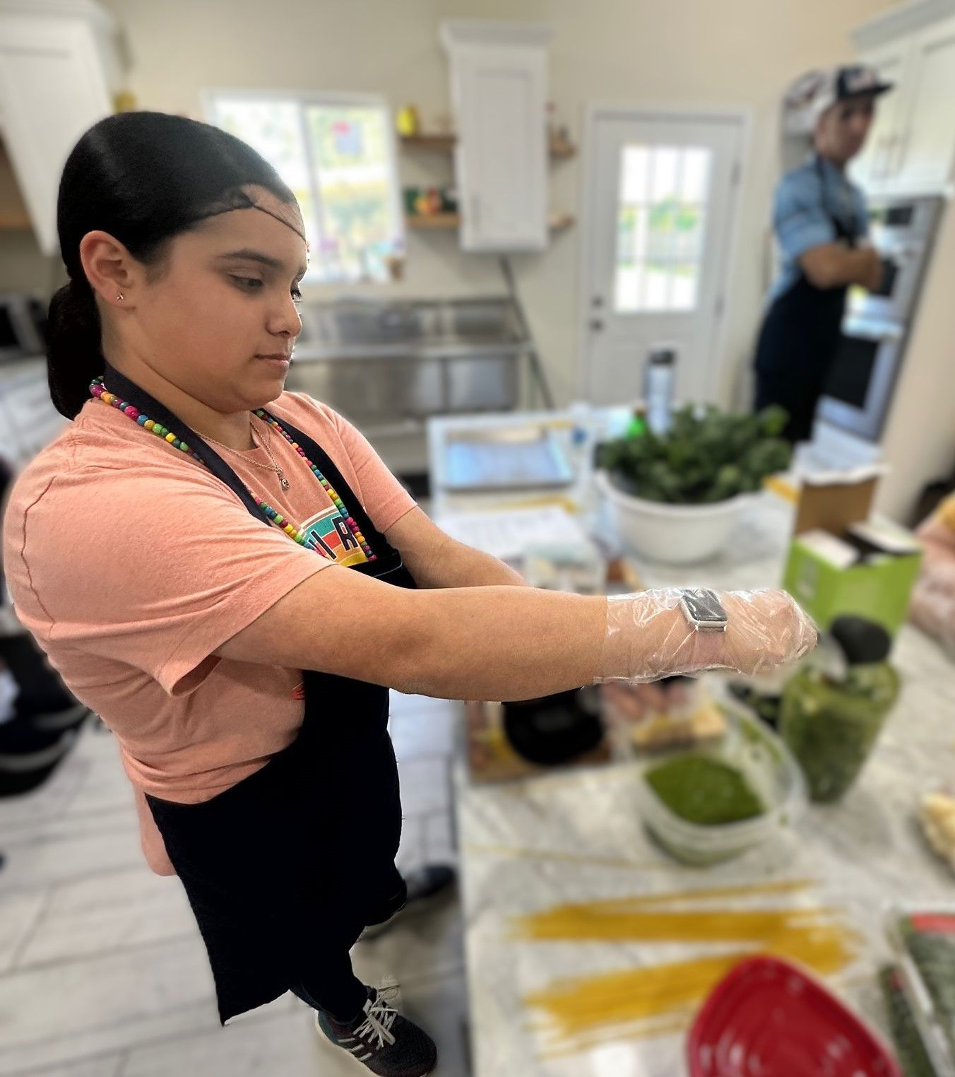 A woman wearing gloves is preparing food in a kitchen.
