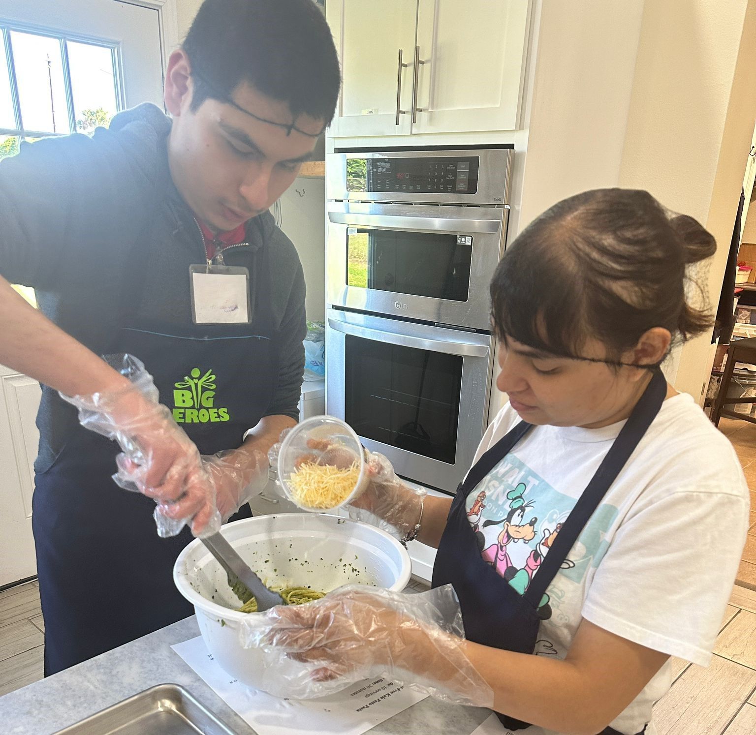 A man and a woman are preparing food in a kitchen and the man is wearing an apron that says big smiles
