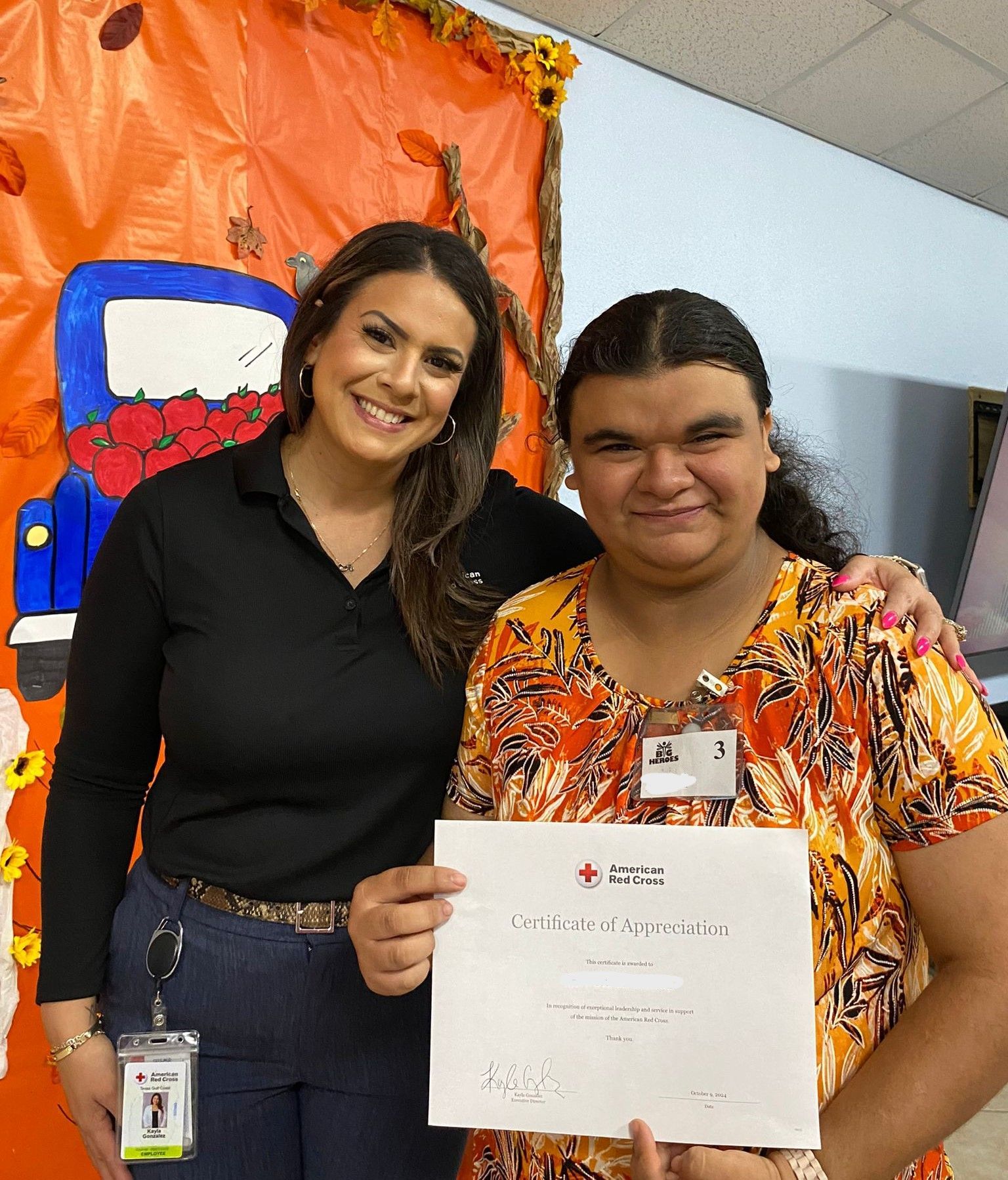 Two women are posing for a picture and one is holding a certificate