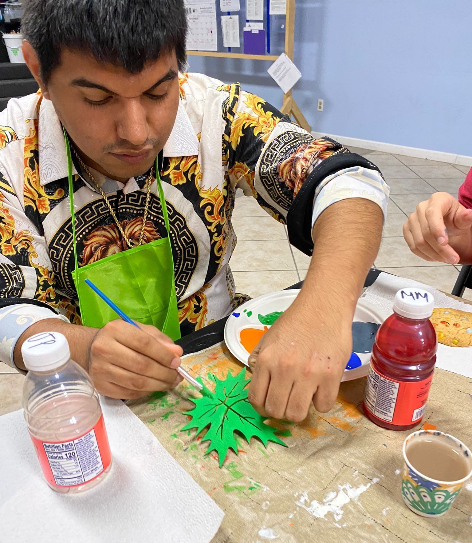 A man wearing a green apron is painting a green leaf