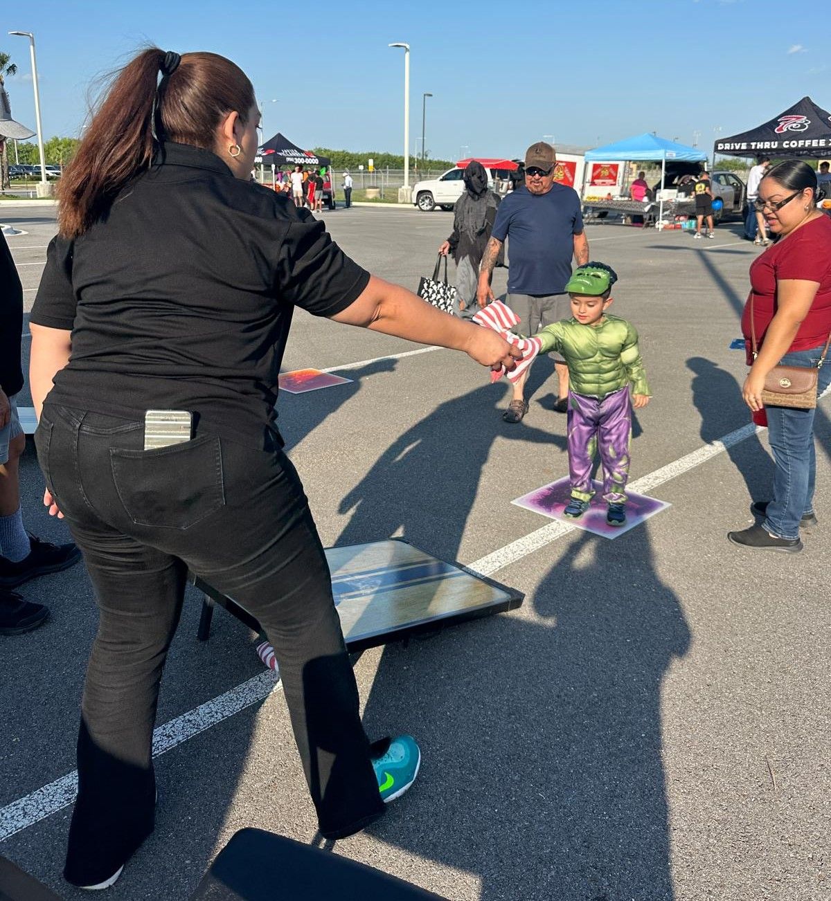 A woman in a black shirt is standing next to a child in a hulk costume